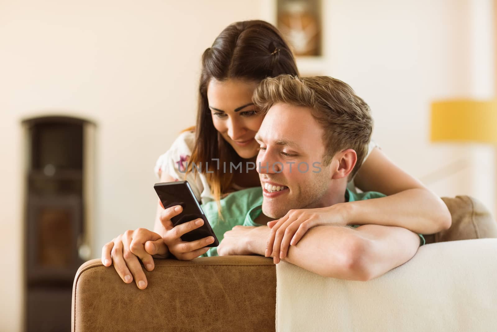 Cute couple looking at smartphone on couch at home in the living room