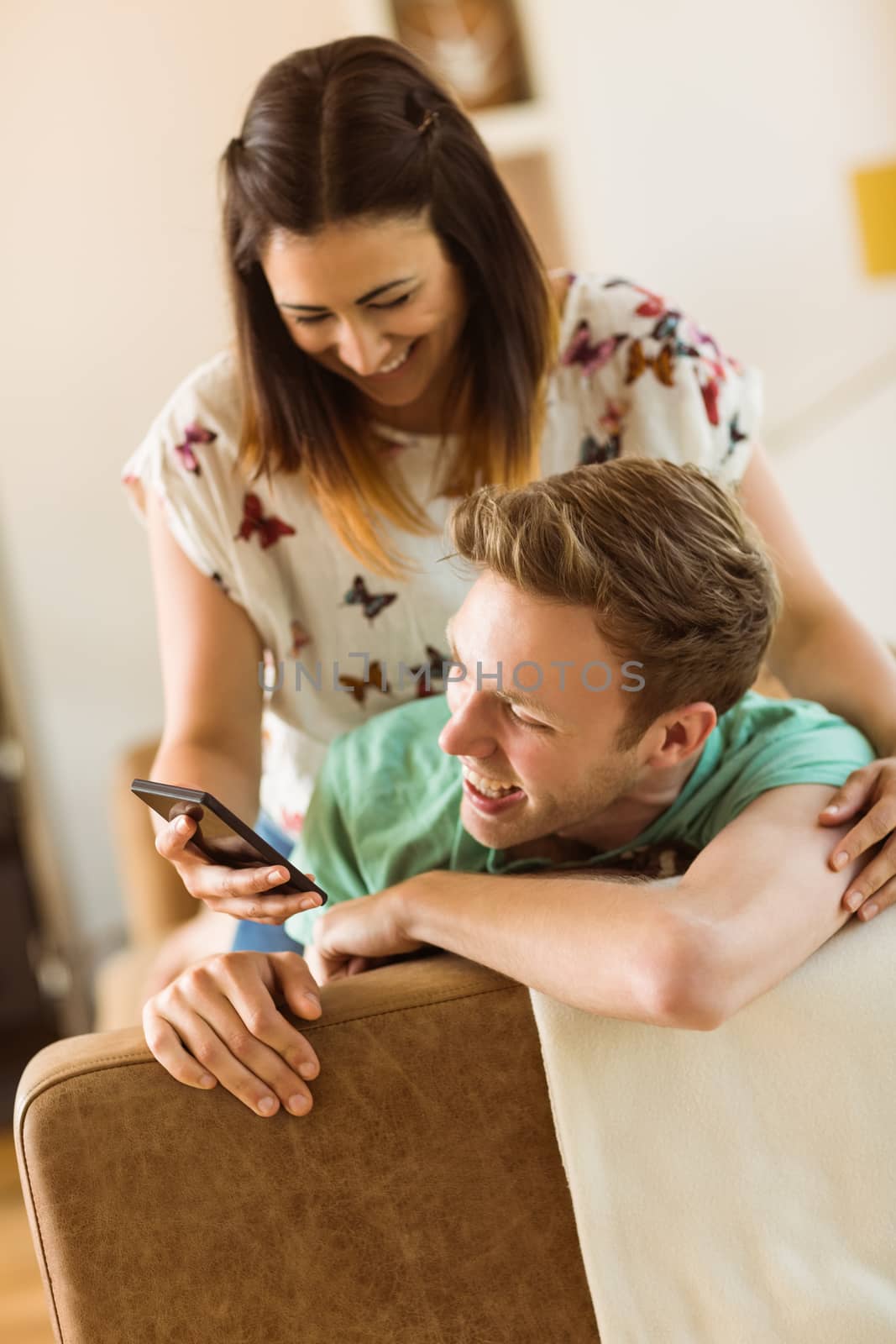 Cute couple looking at smartphone on couch at home in the living room