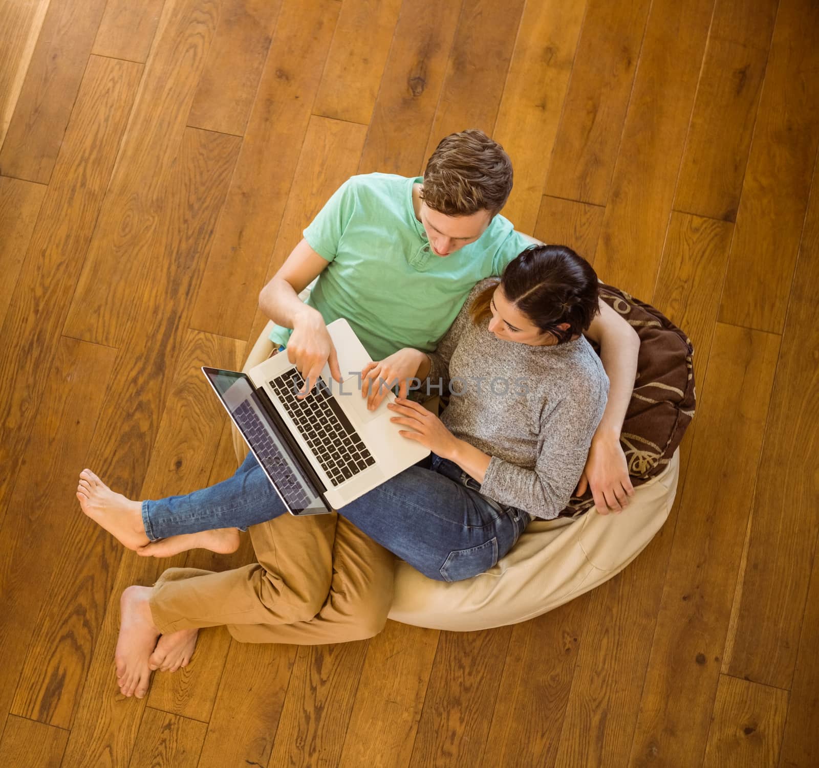 Cute couple using laptop on beanbag at home in the living room