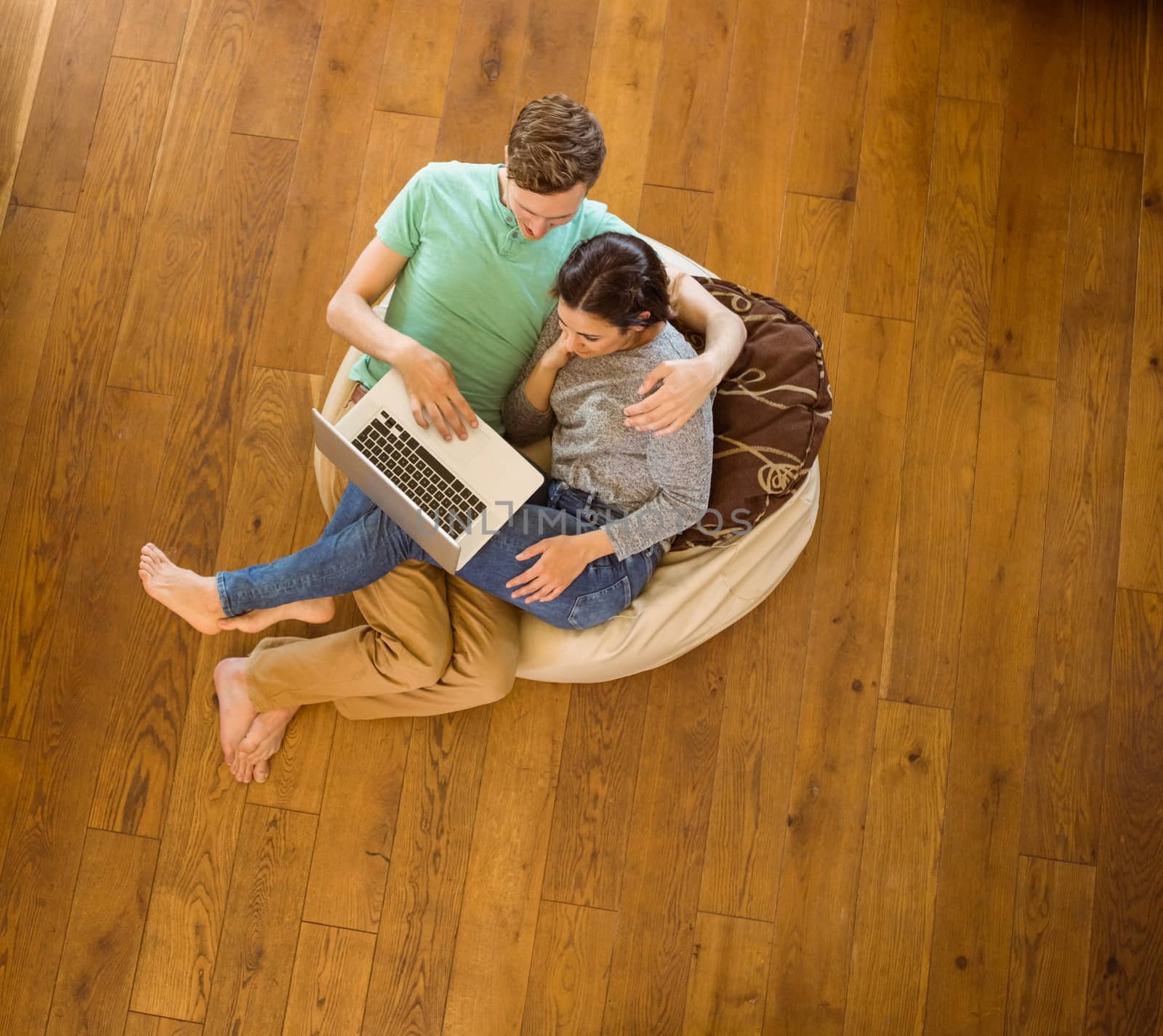Cute couple using laptop on beanbag at home in the living room