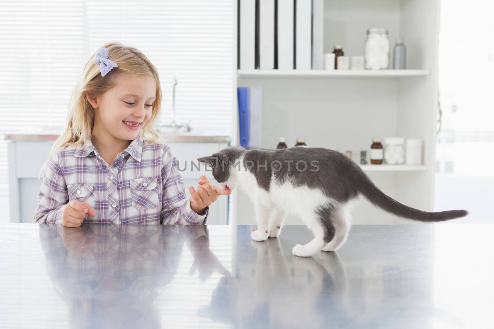 Smiling blonde owner petting her kitten in medical office