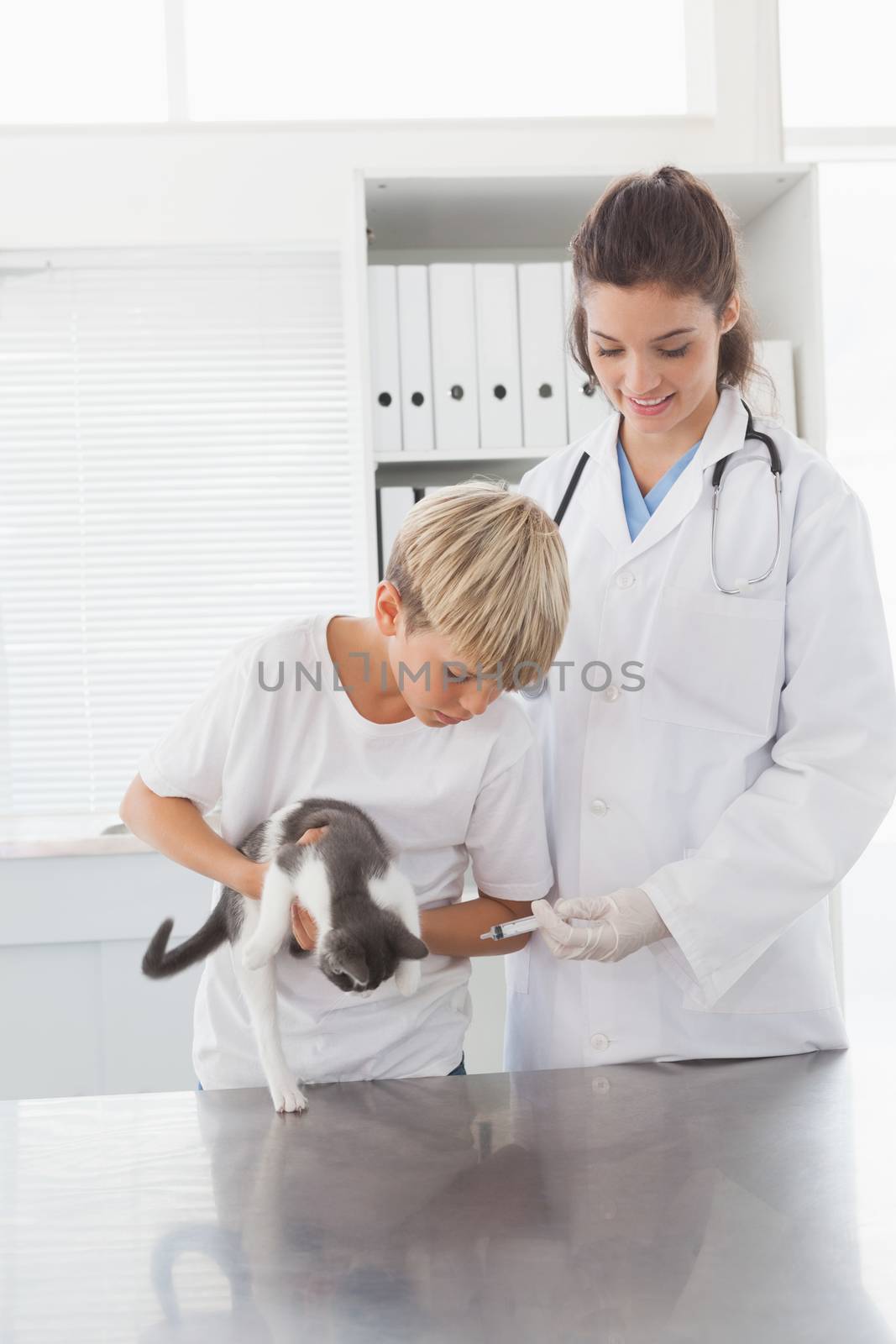 Smiling vet examining a cat with its owner in medical office