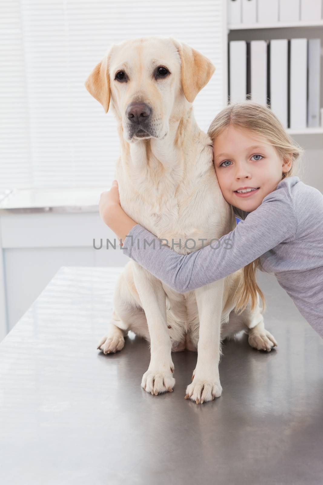 Blonde owner hugging her cute dog in medical office