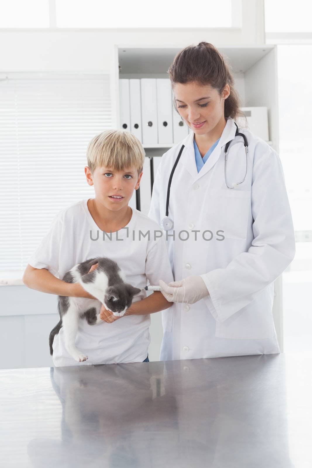 Smiling vet examining a cat with its owner  by Wavebreakmedia