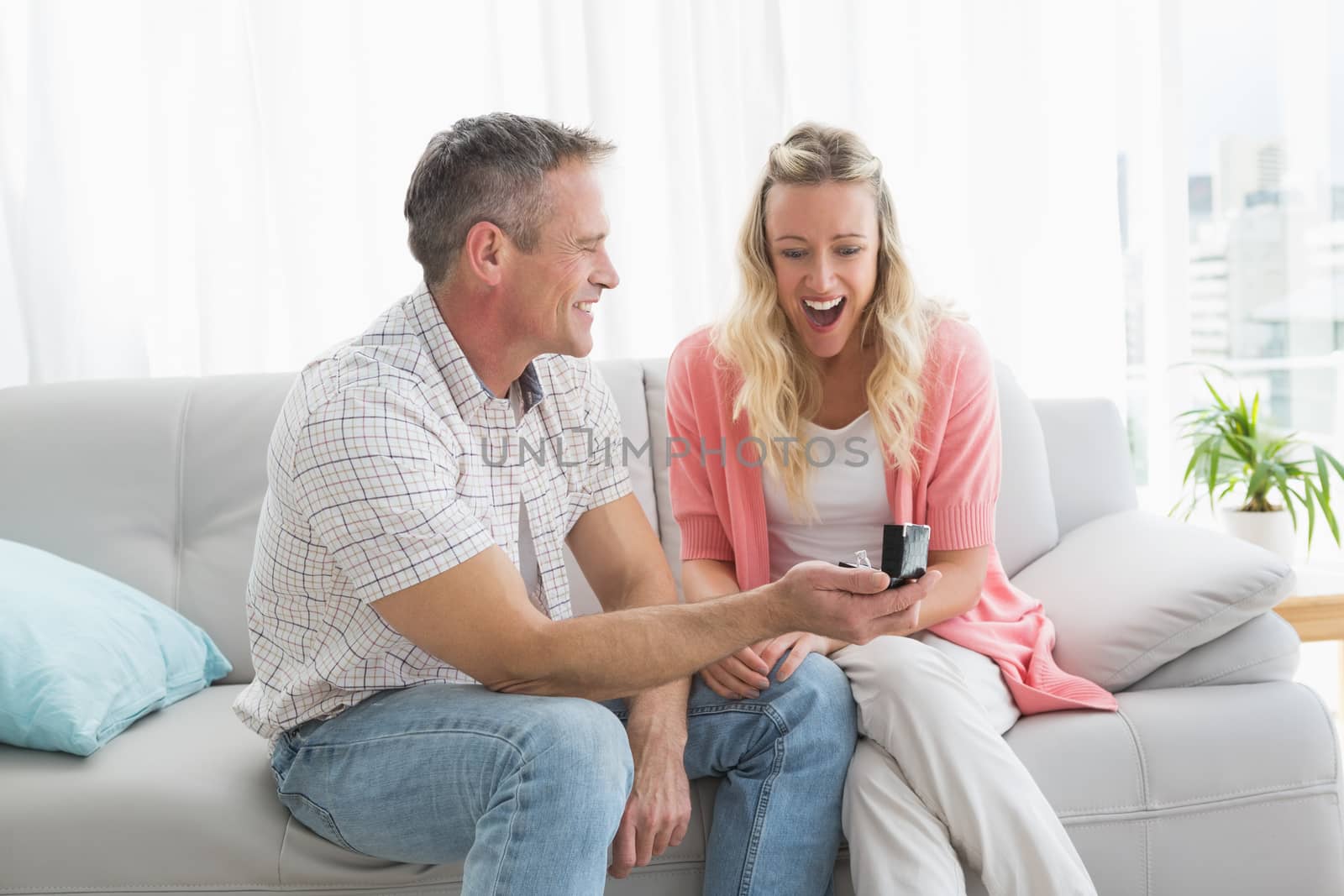 Man offering a romantic gift to his girlfriend at home in the living room