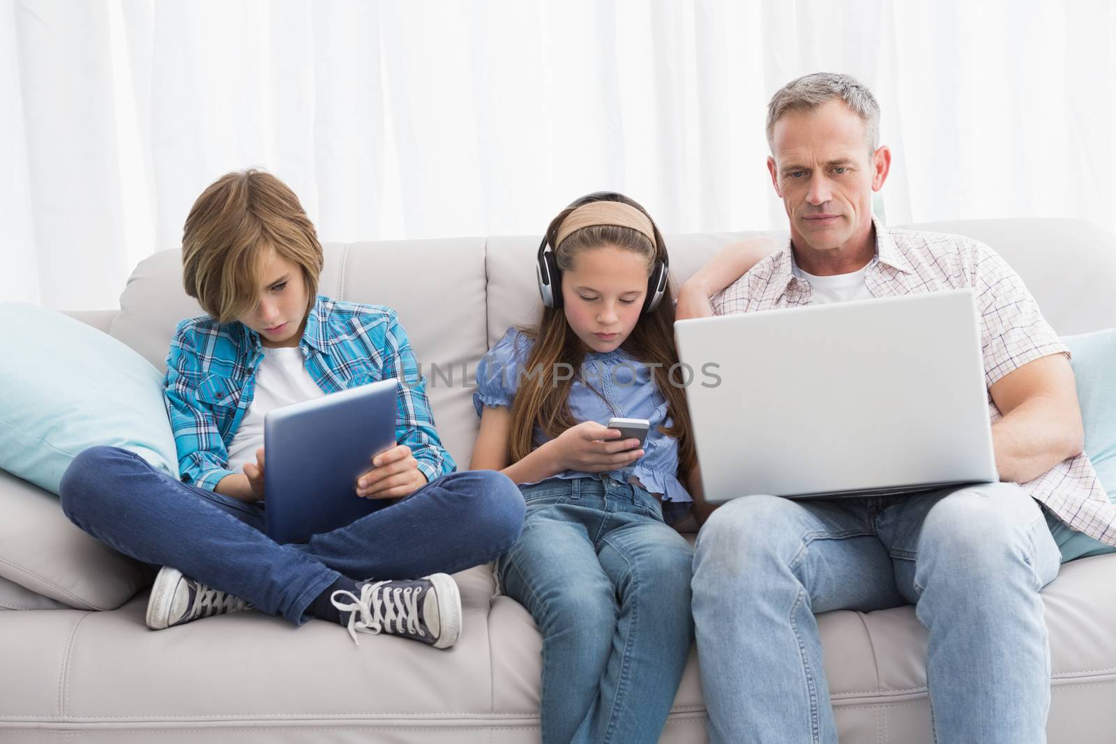 Family focus on wireless technology at home in the living room