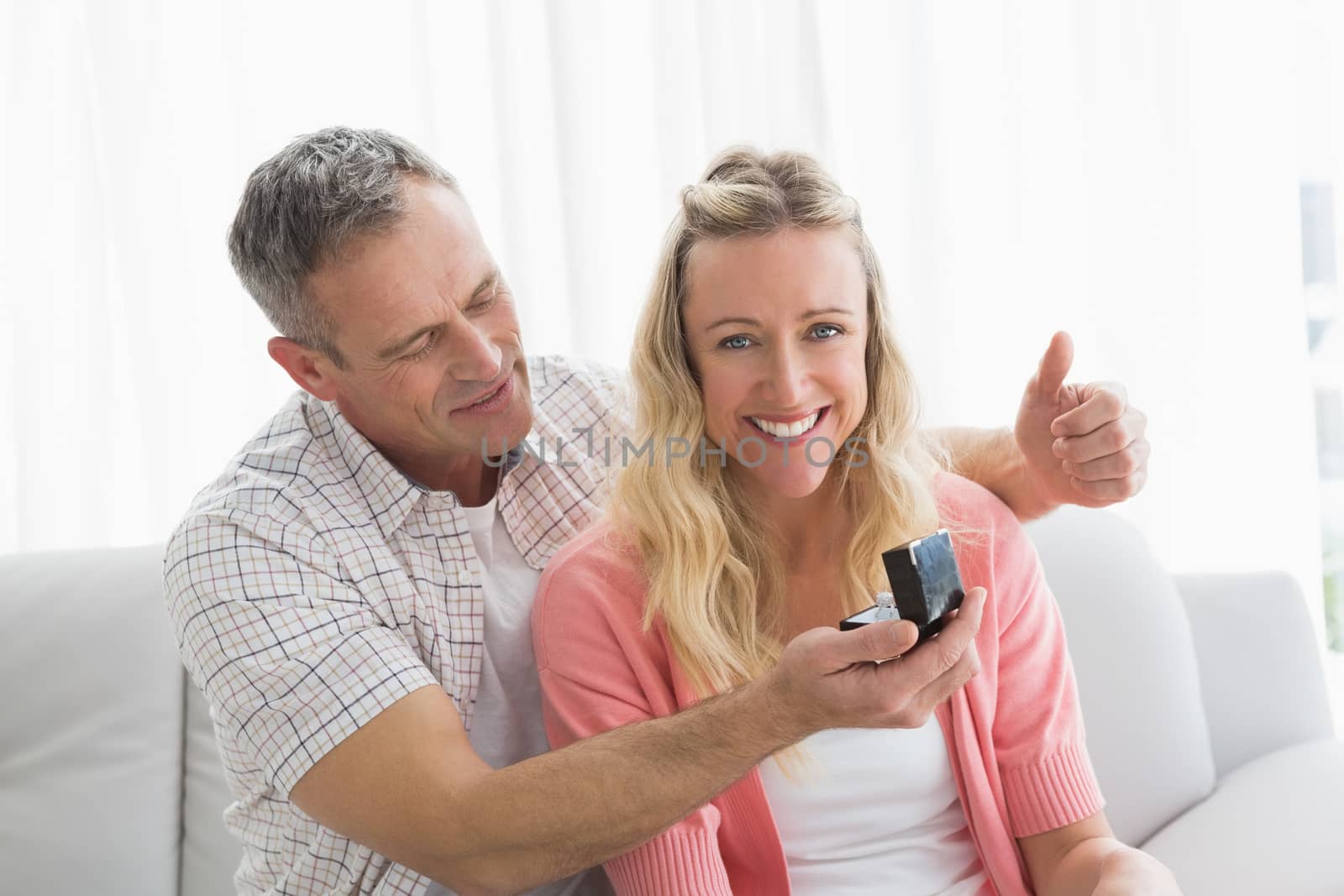 Man offering a romantic gift to his girlfriend at home in the living room