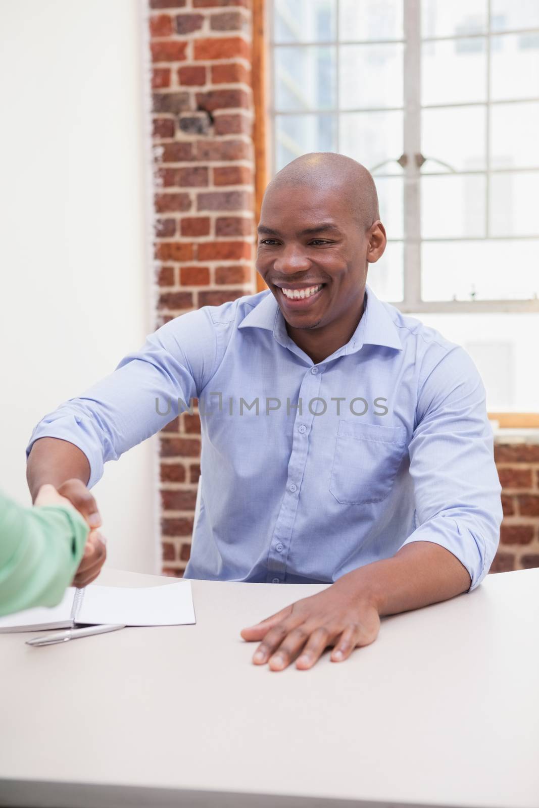 Casual business people shaking hands at desk in the office