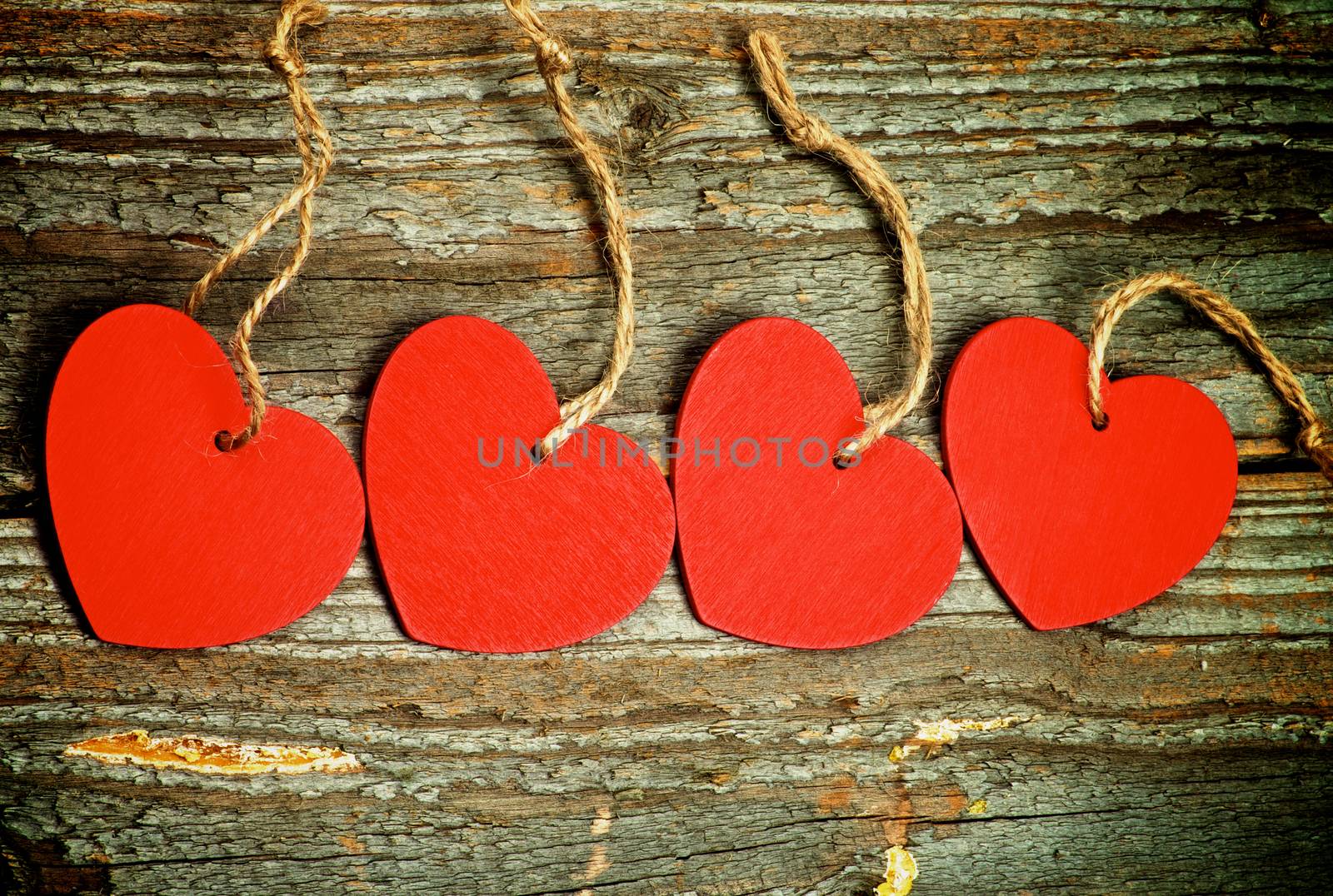 Handmade Red Hearts with Ropes In a Row on Rustic Wooden background