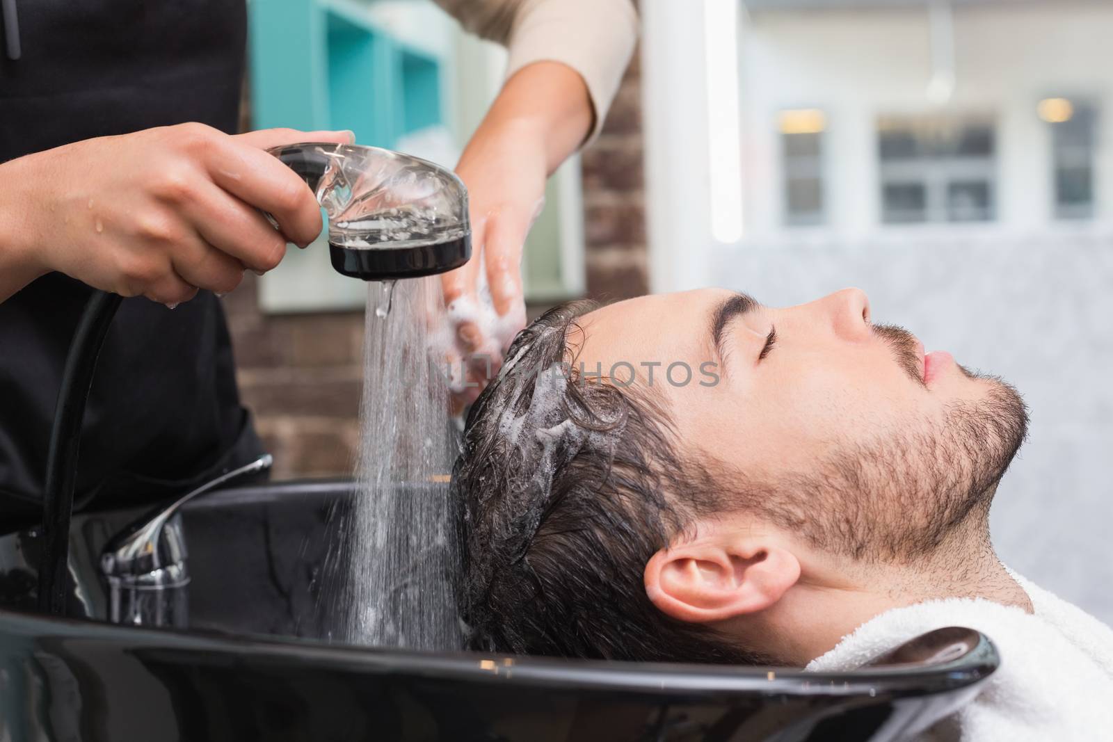 Hair stylist washing mans hair by Wavebreakmedia