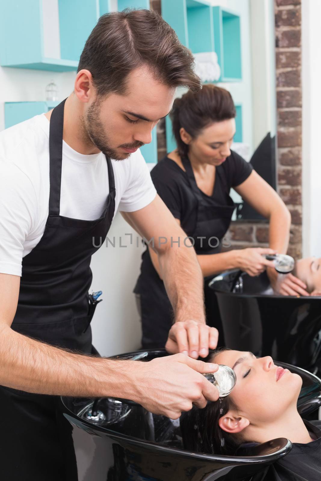 Hairdressers washing their clients hair by Wavebreakmedia