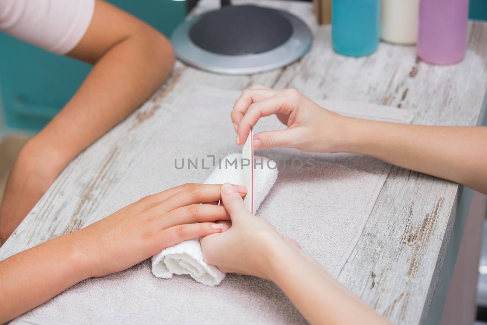 Nail technician giving manicure to customer at the beauty salon