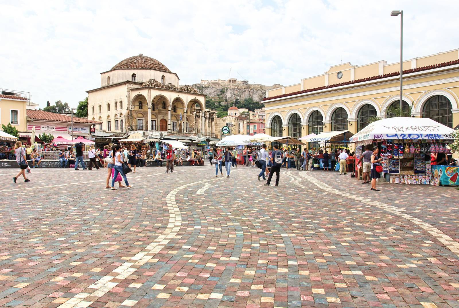 ATHENS, GREECE - MAY 19, 2015: Financial crisis in Greece. Athenians and tourists in Monastiraki Square, with market stalls, underground station on right, Tzistarakis Mosque on left and the Acropolis in the background.