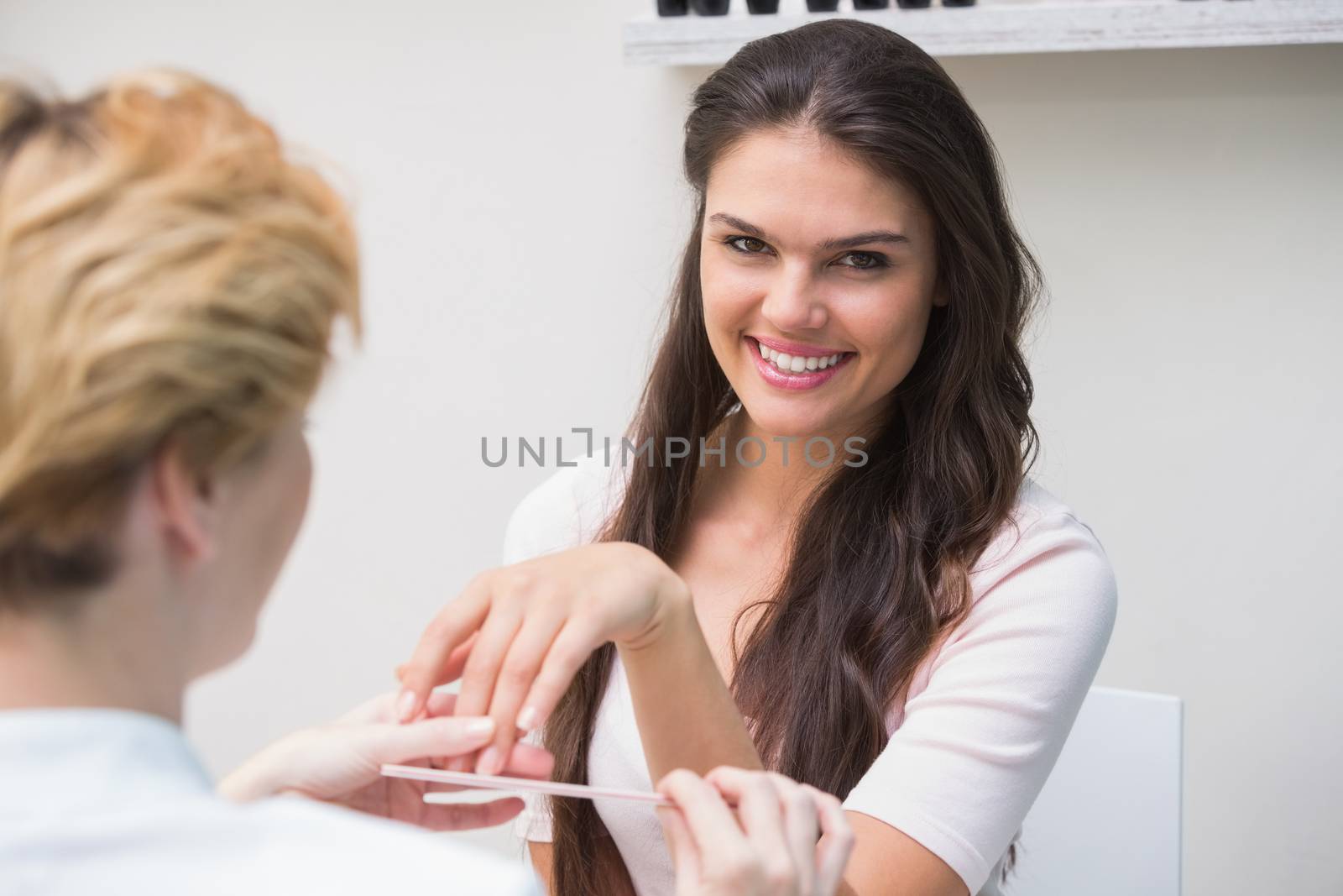 Pretty nail technician giving manicure to customer at the beauty salon