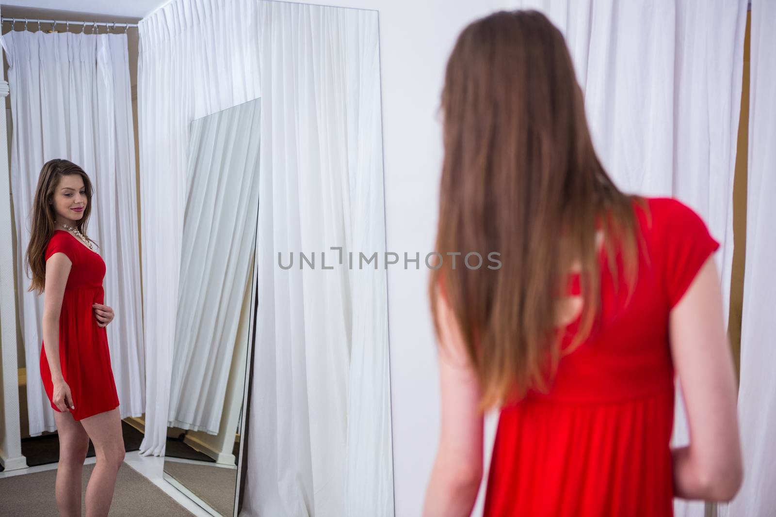 Woman trying on a red dress in fashion boutique