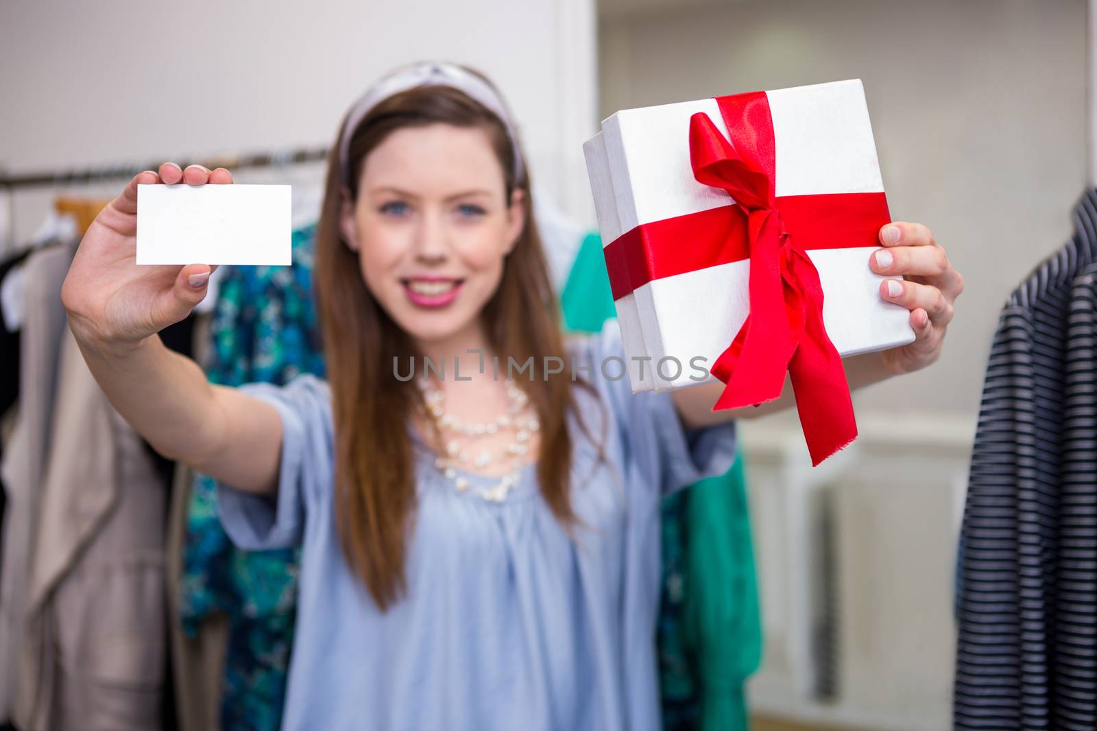 Brunette showing gift and card to camera in fashion boutique