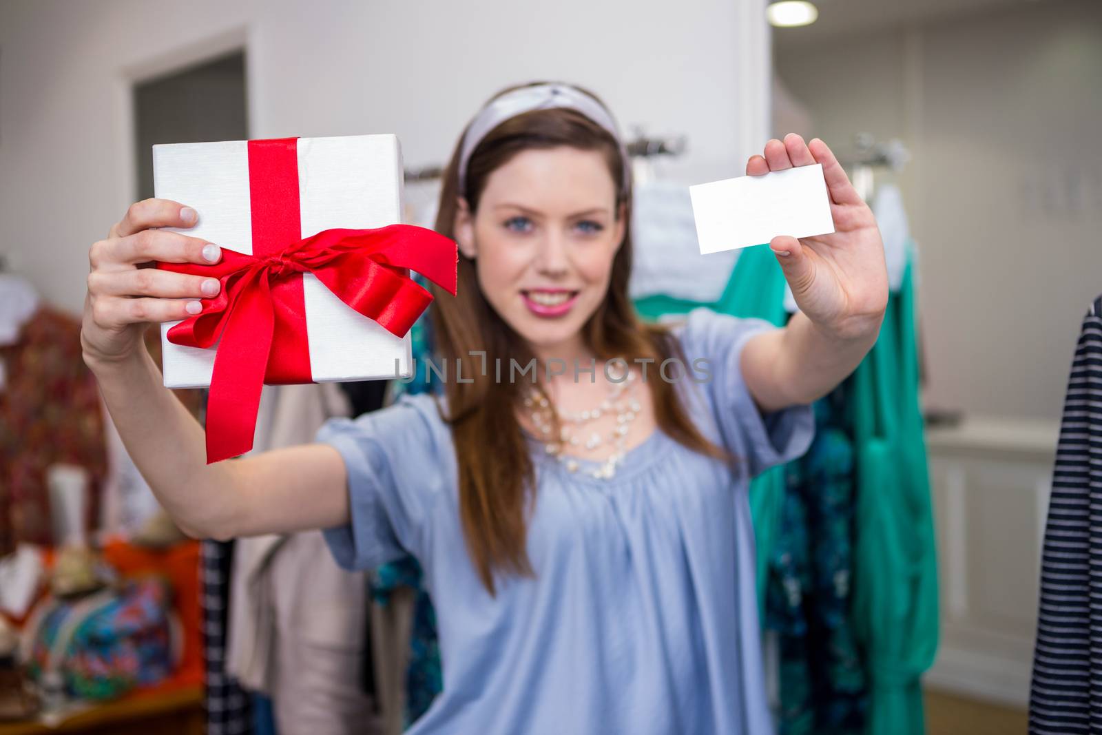 Brunette showing gift and card to camera in fashion boutique