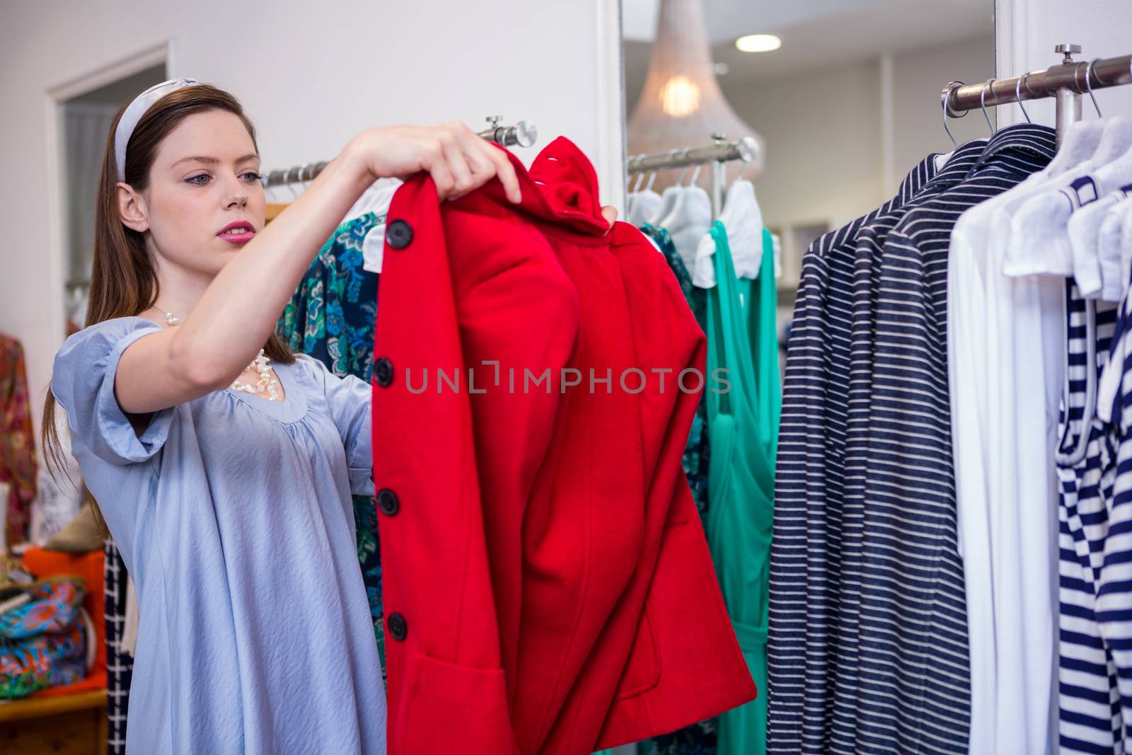 Brunette trying on a red coat by Wavebreakmedia