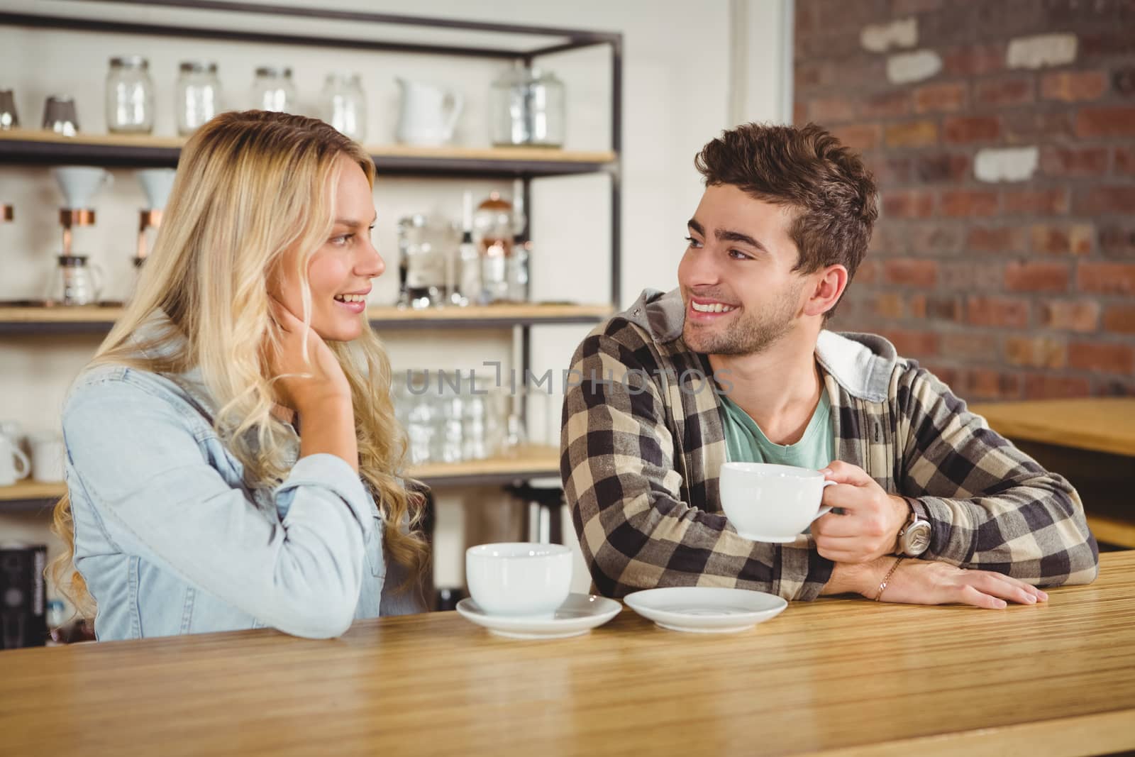 Smiling hipsters sitting and enjoying coffee together at coffee shop