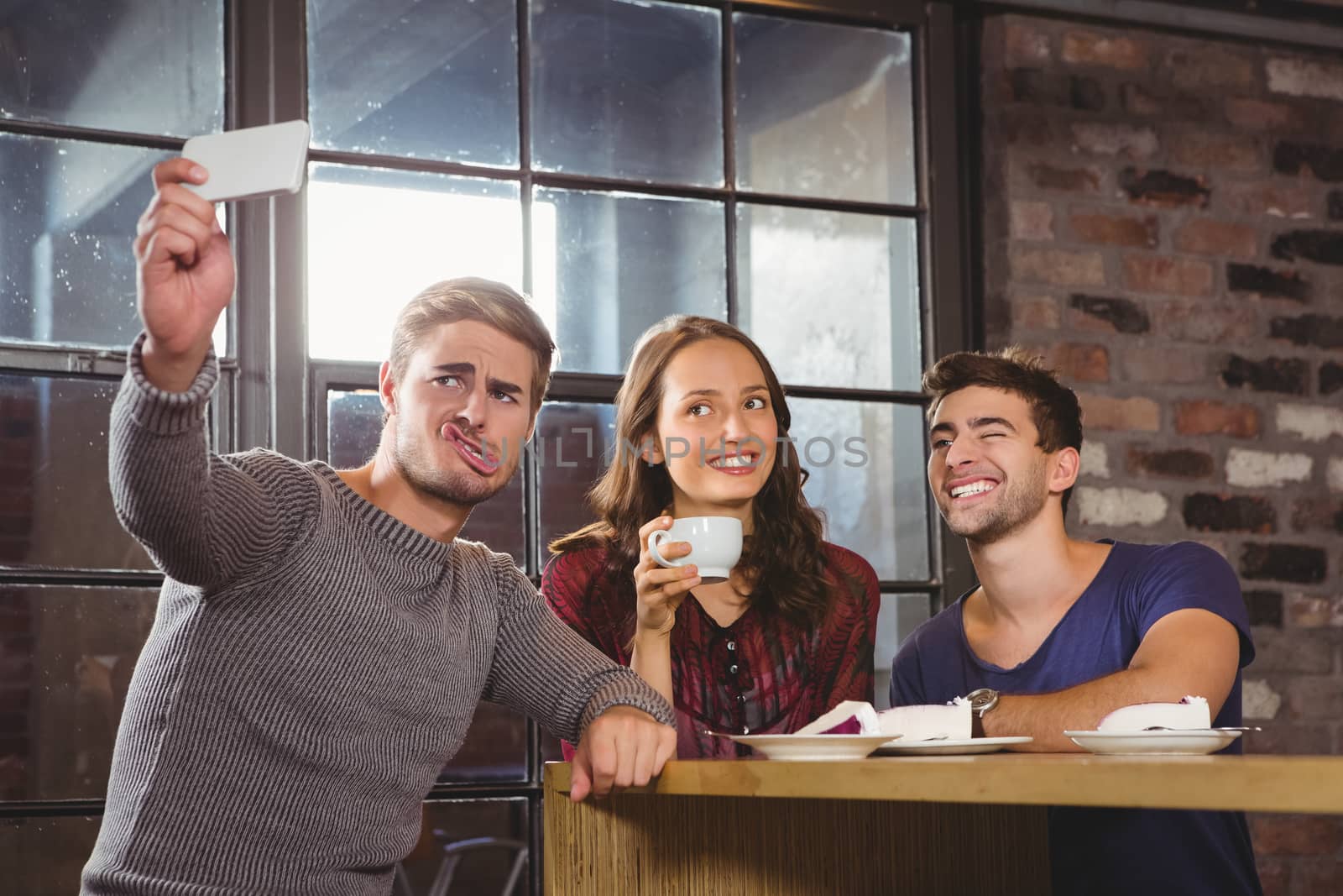 Friends having coffee and taking funny selfies at coffee shop