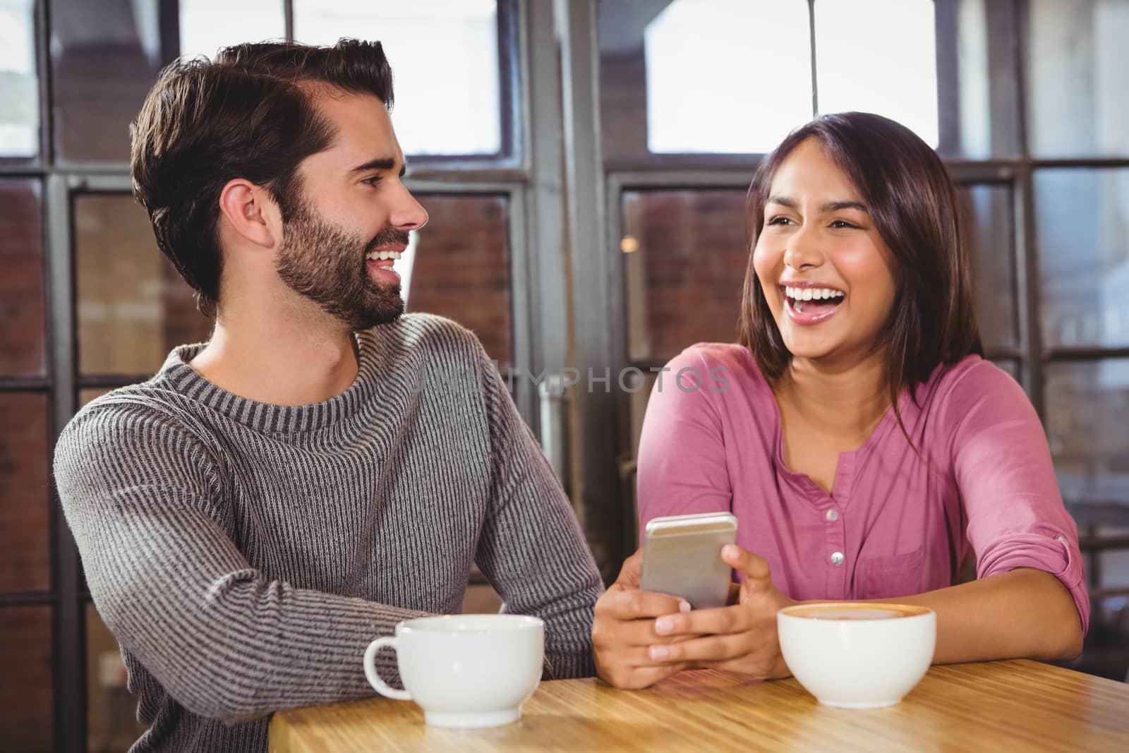 Cute couple looking at a smartphone at a cafe