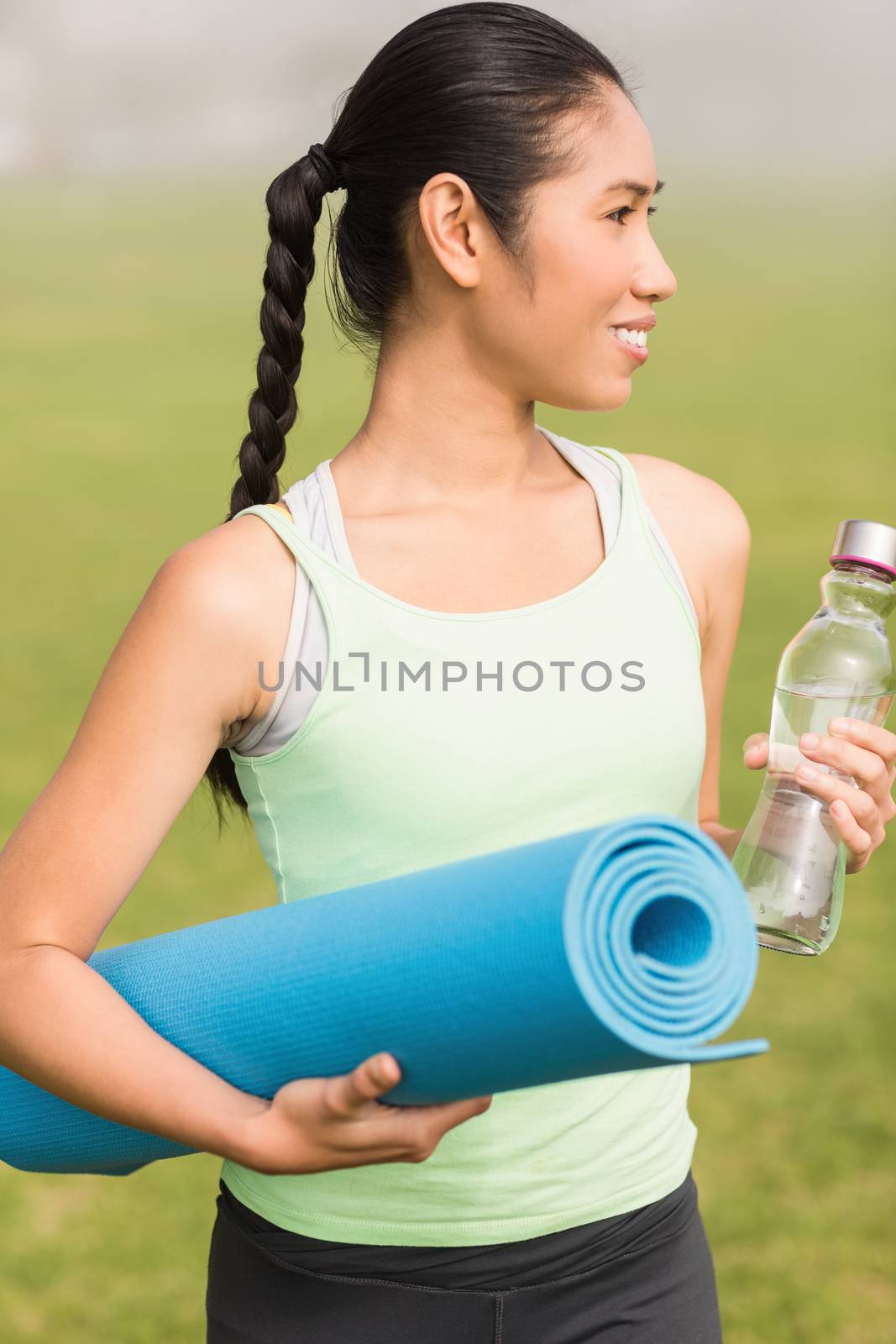 Sporty woman holding exercise mat and water bottle by Wavebreakmedia