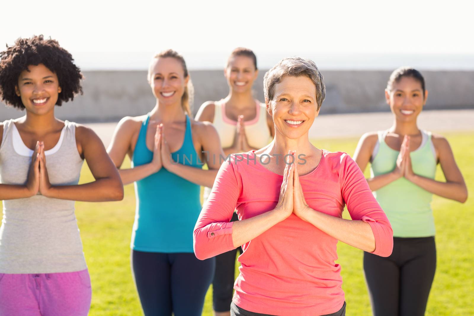 Portrait of smiling sporty women doing prayer position in yoga class in parkland