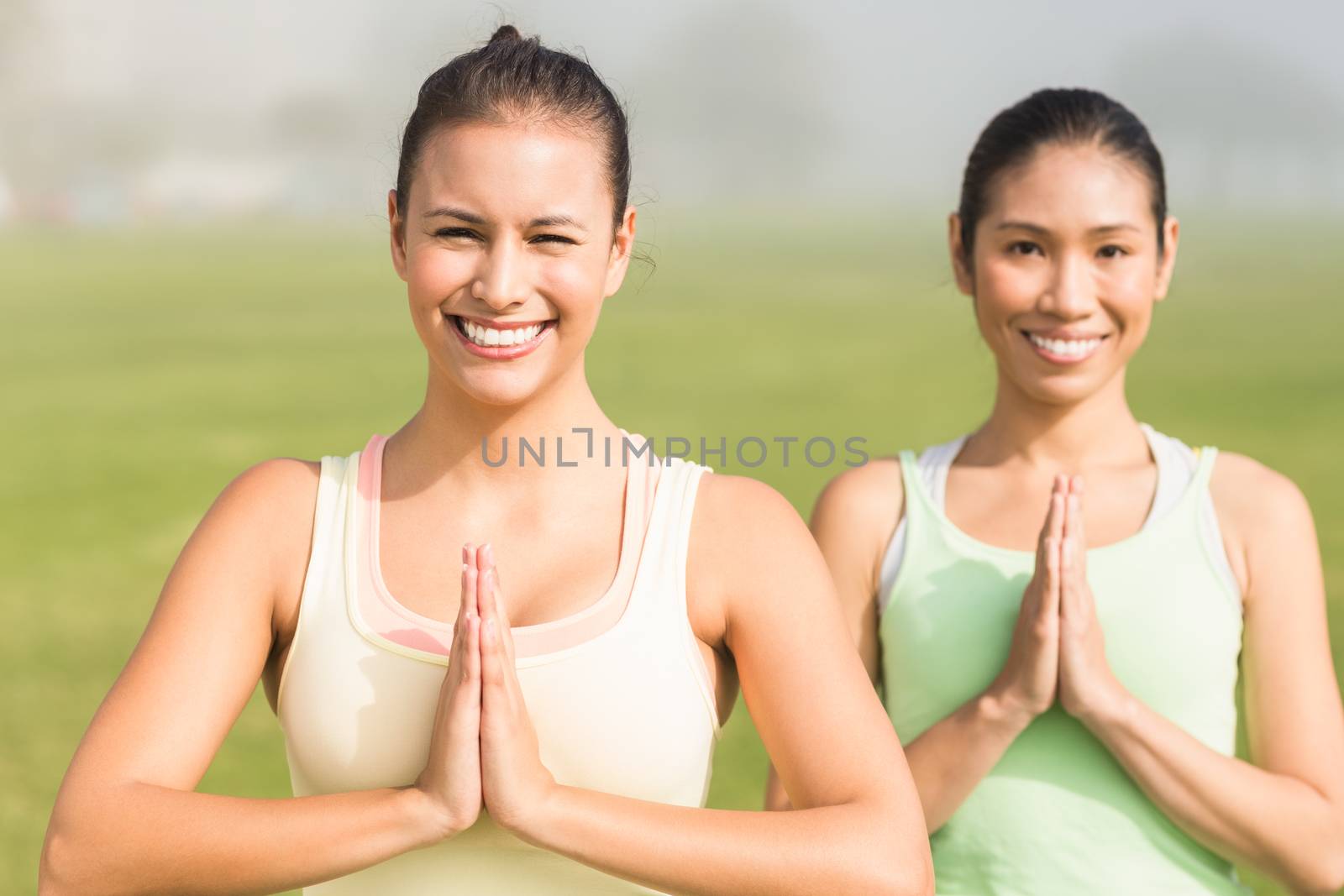 Smiling sporty women doing yoga by Wavebreakmedia