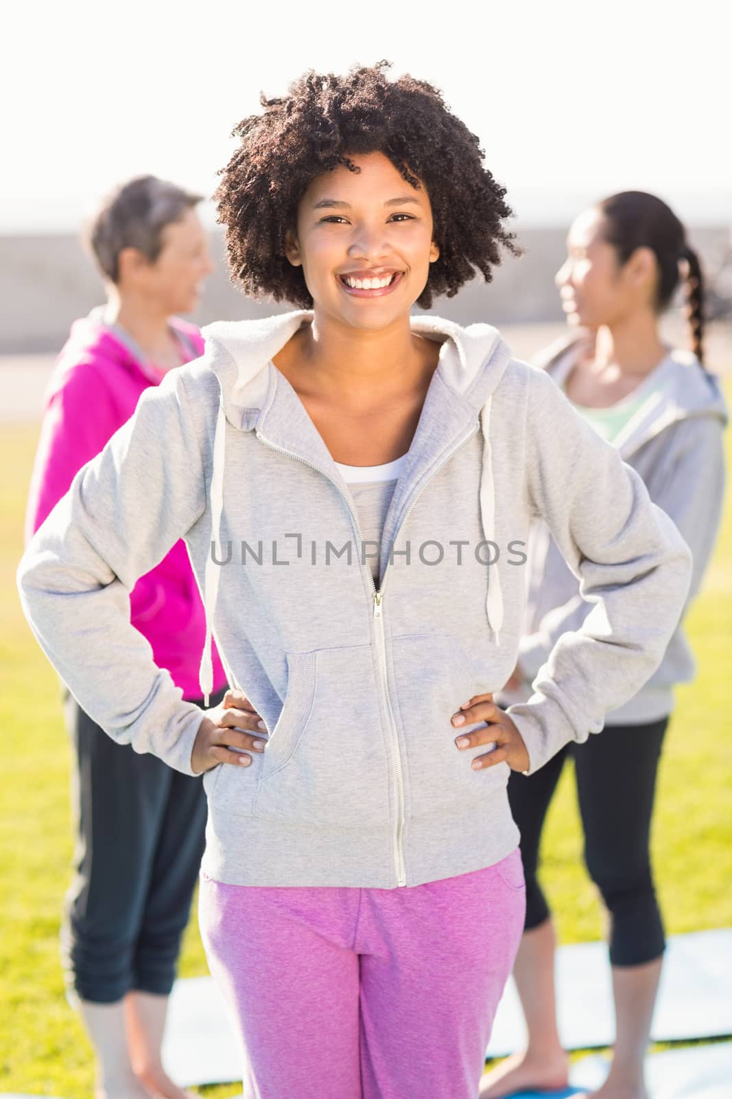 Portrait of sporty woman with hands on hips in front of friends in parkland