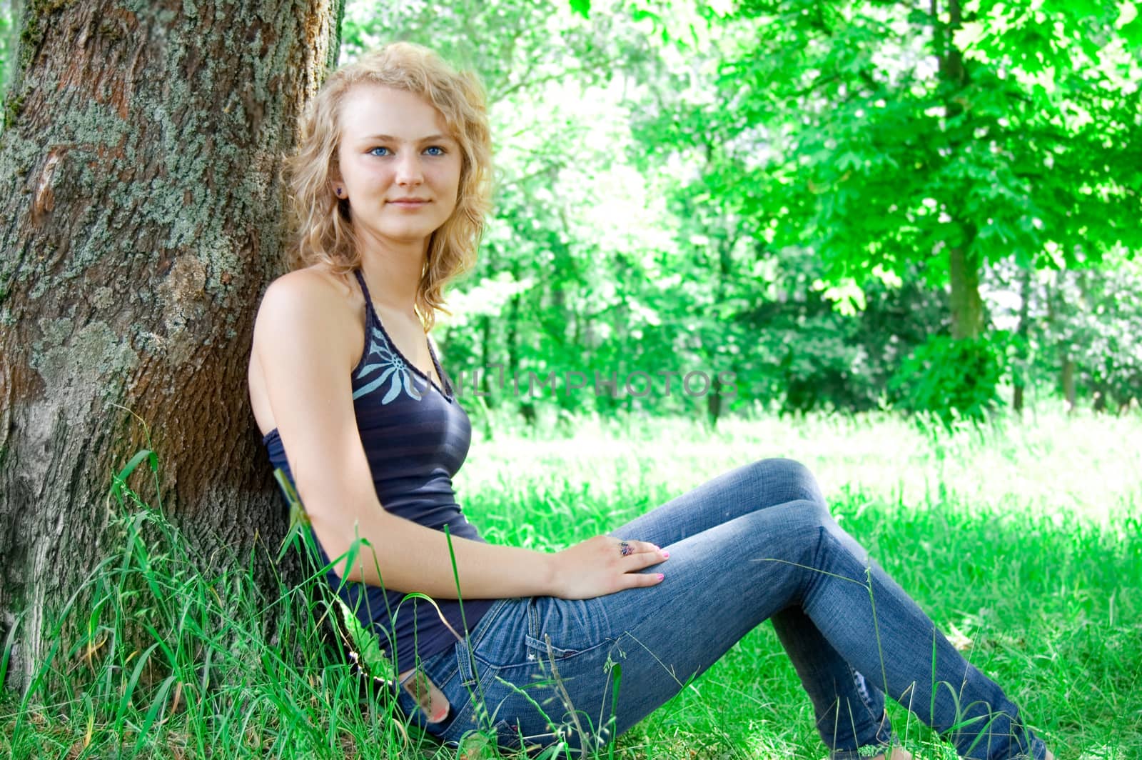 Portrait of young beautiful girl based on the park tree.