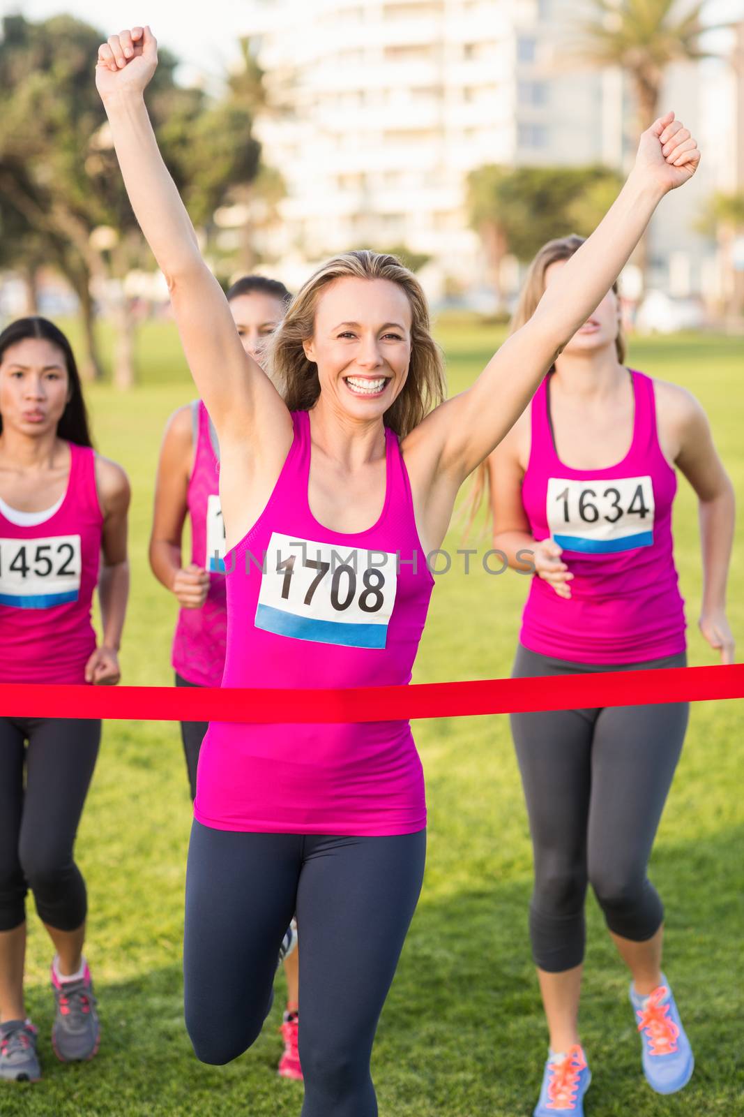 Portrait of cheering blonde winning breast cancer marathon in parkland