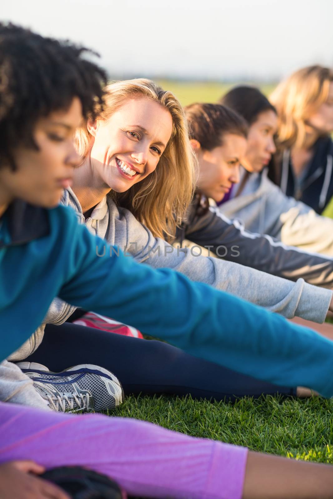 Portrait of smiling sporty blonde stretching during fitness class in parkland