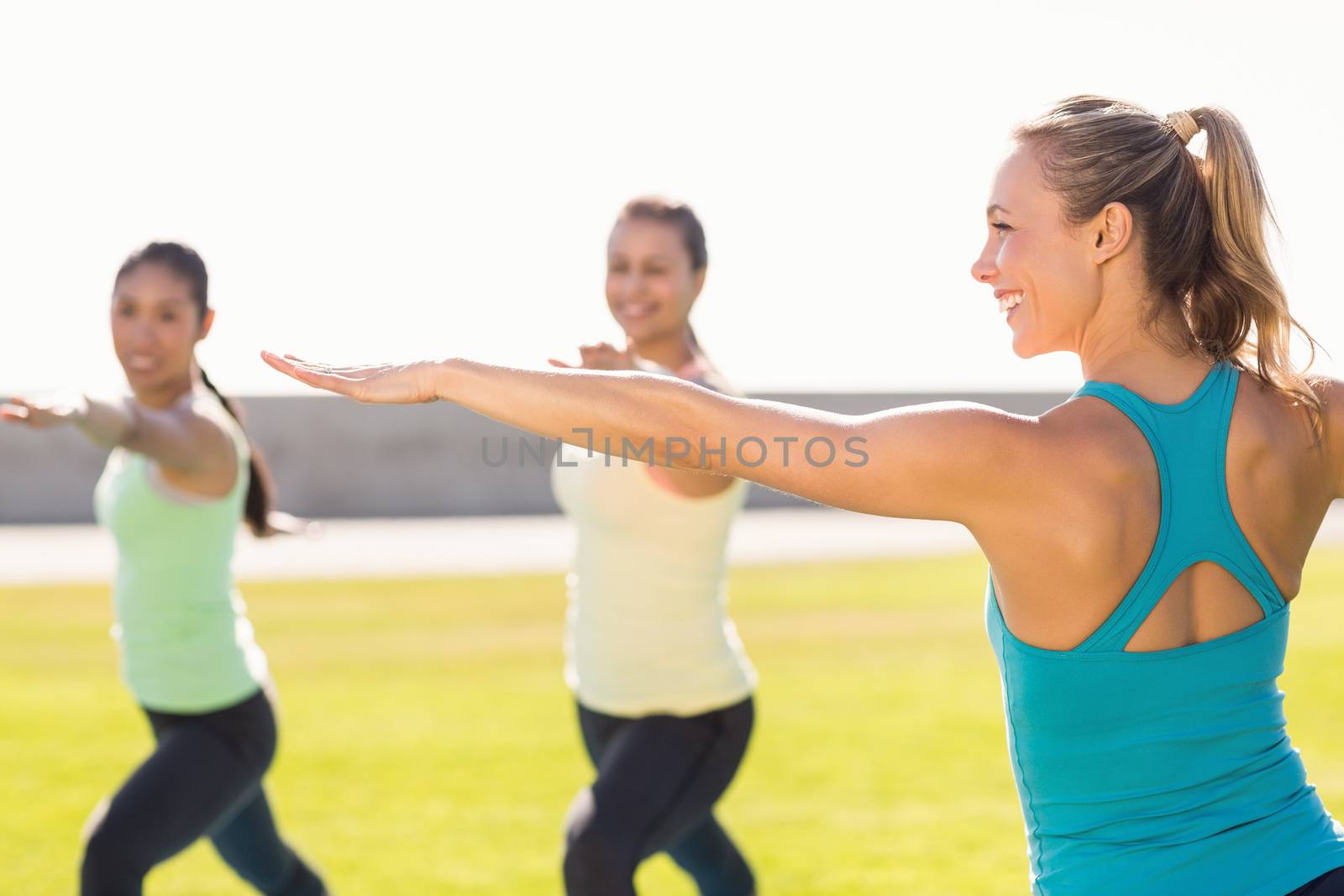 Yoga teacher and sporty women attending yoga class in parkland