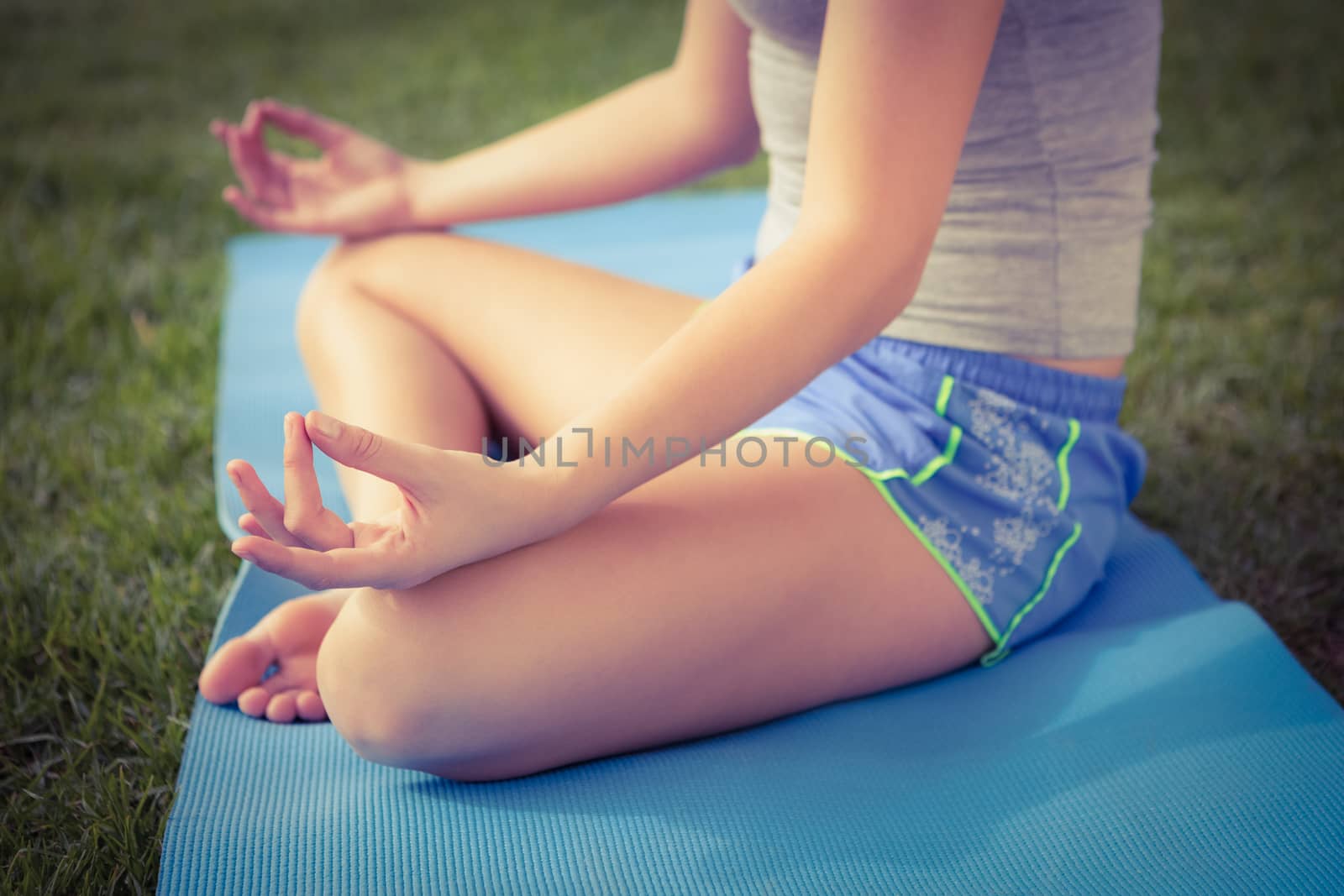 Sporty woman meditating on exercise mat in parkland