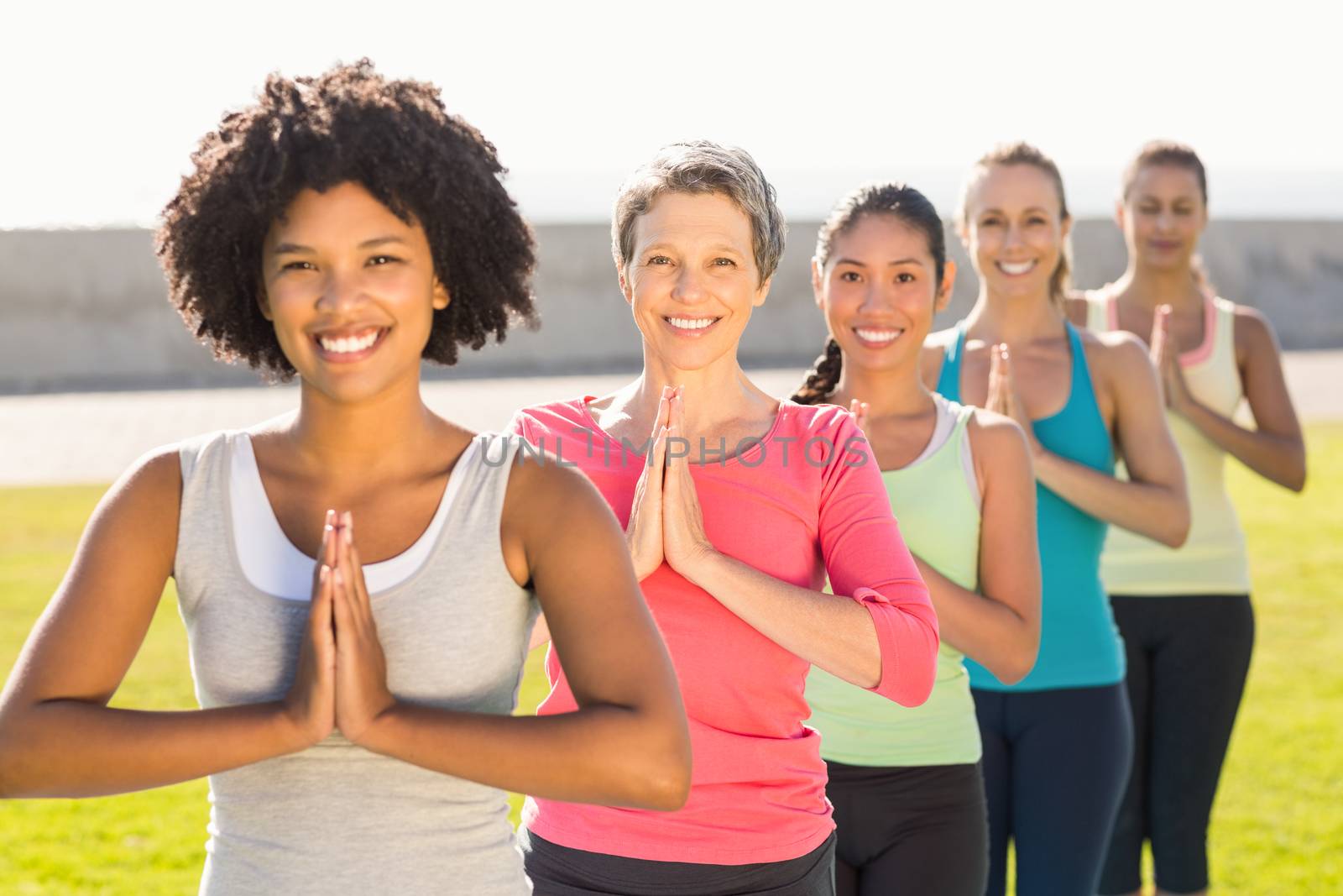 Portrait of smiling sporty women doing prayer position in yoga class in parkland