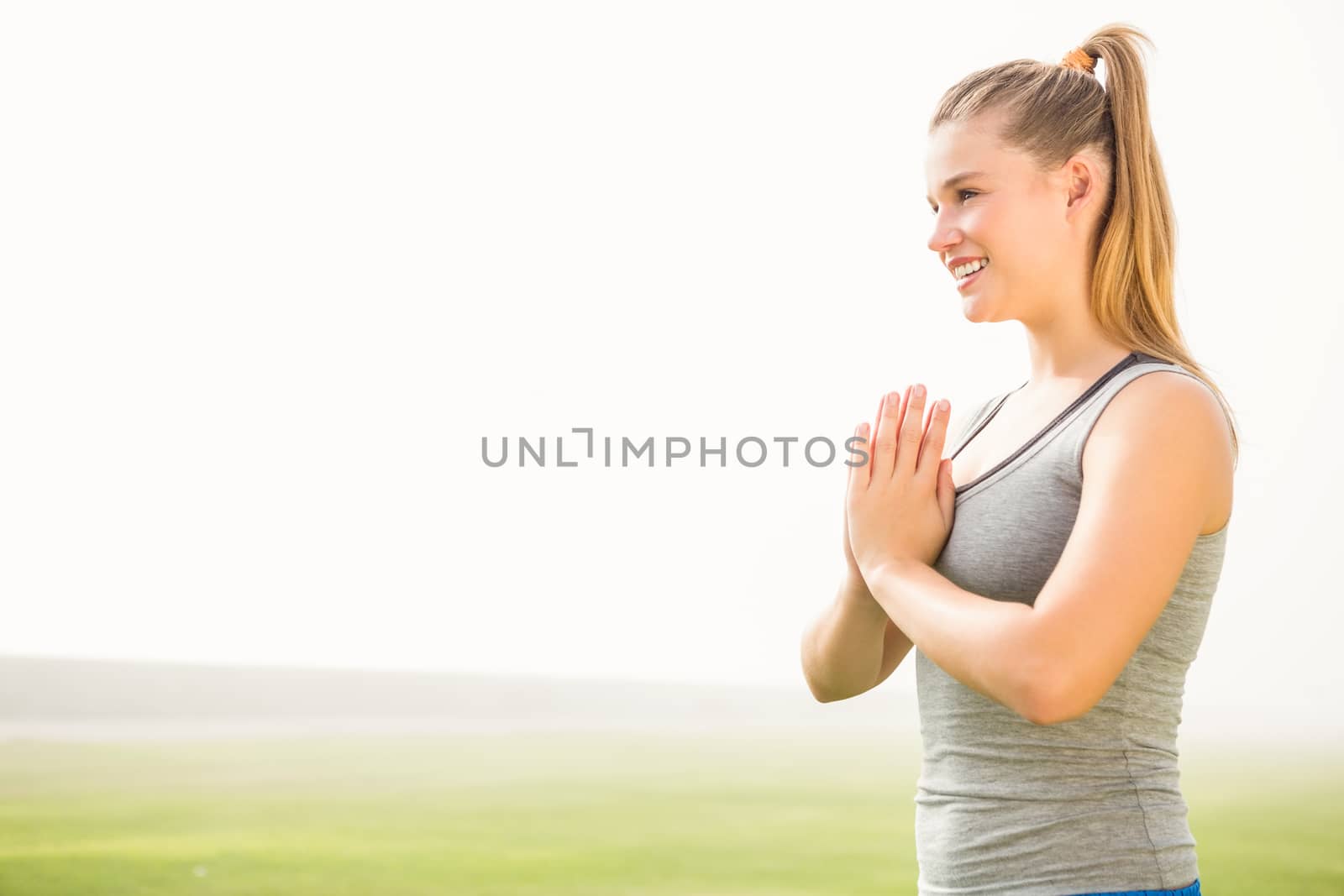 Smiling sporty blonde meditating in parkland