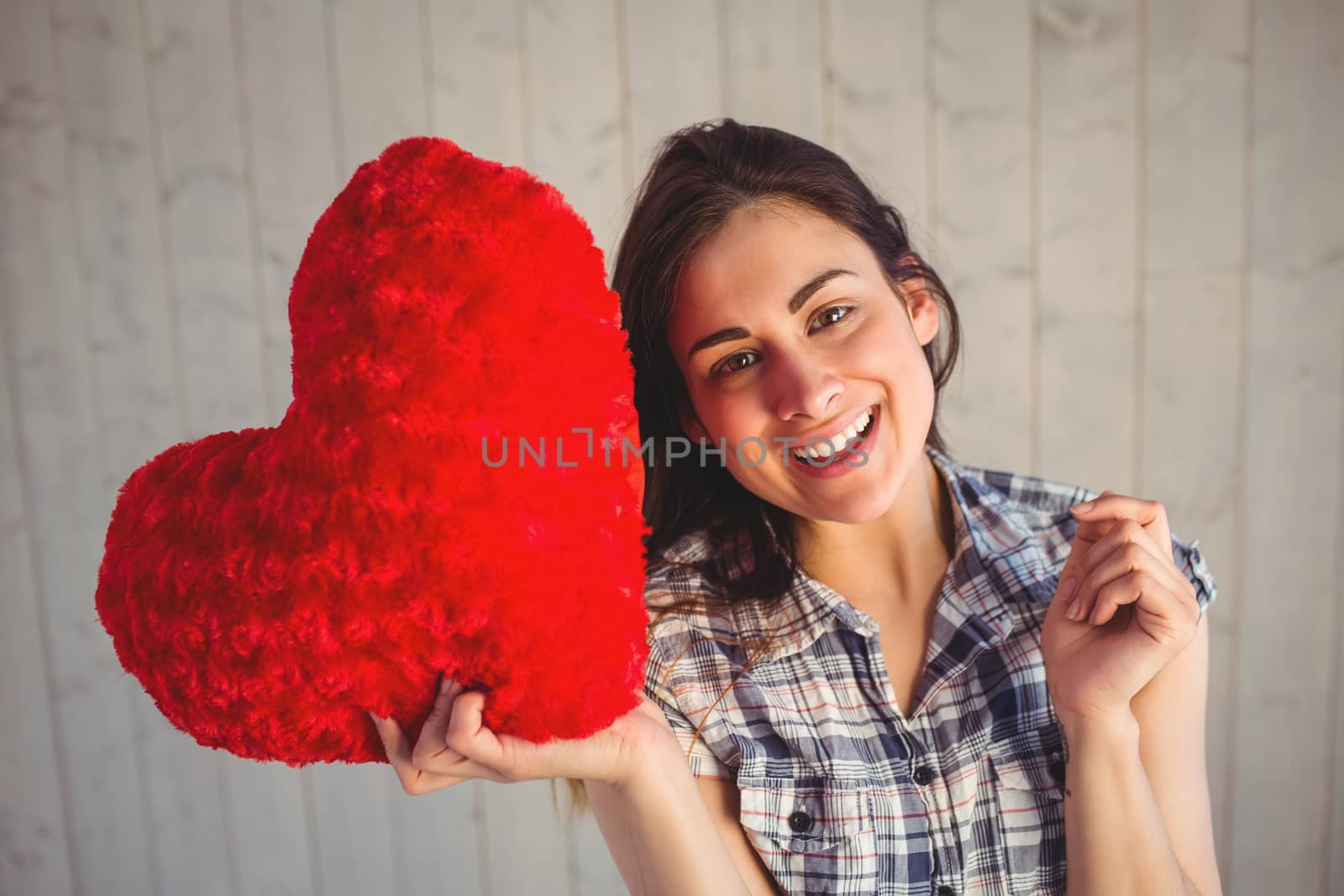 Pretty hipster holding heart pillow by Wavebreakmedia