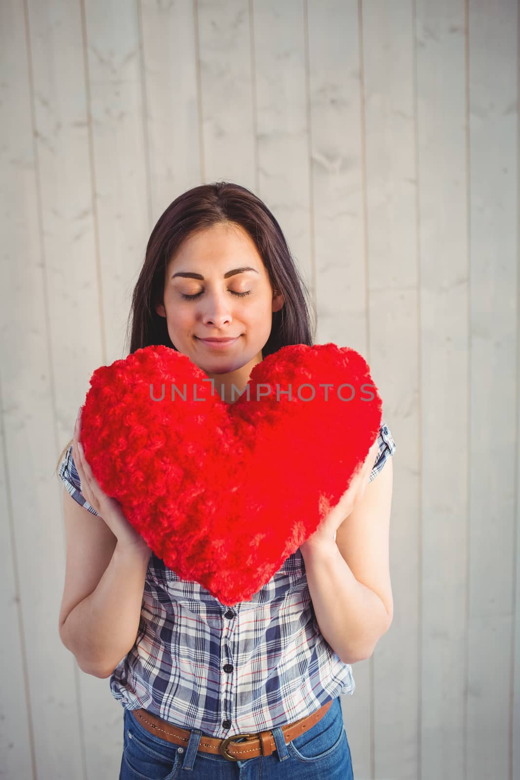 Pretty hipster holding heart pillow on wooden planks background