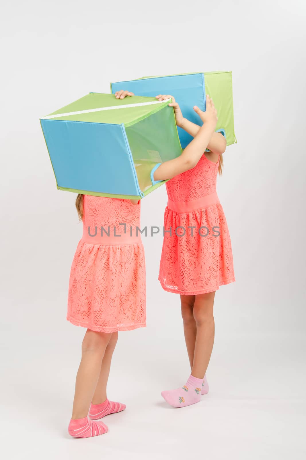Two girls wearing a box on his head, isolated on a light background