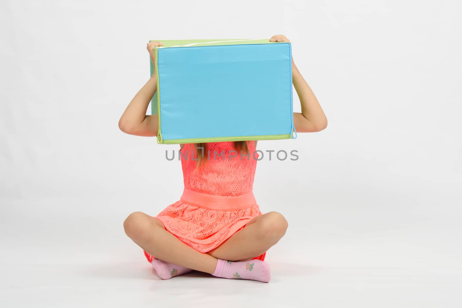 Six year old girl wearing a European-style box on his head, isolated on a light background