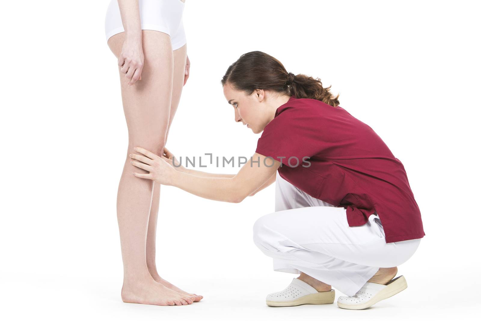 Physiotherapist doing a knee evaluation by Flareimage