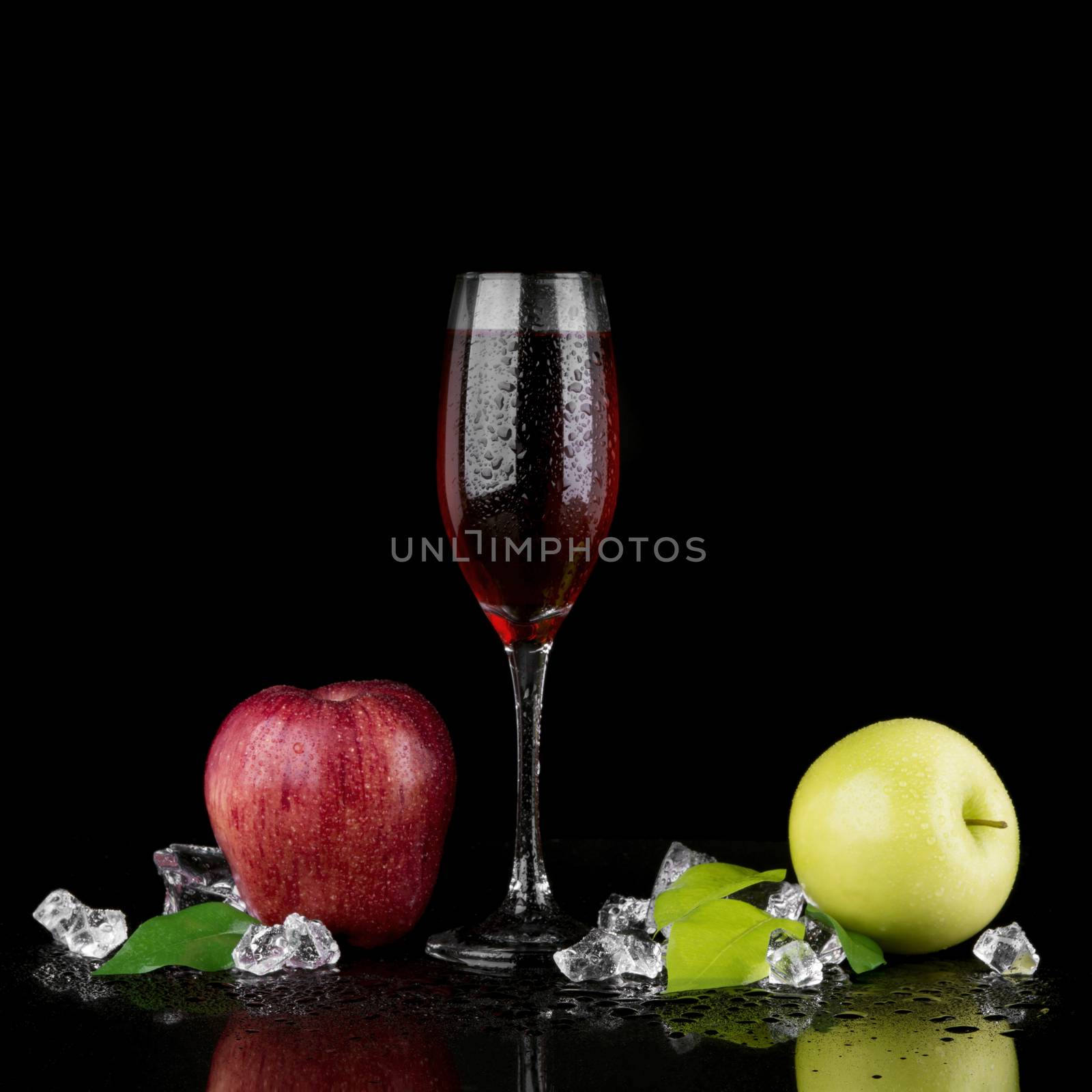 Green and red apple with a glass of champagne on black background