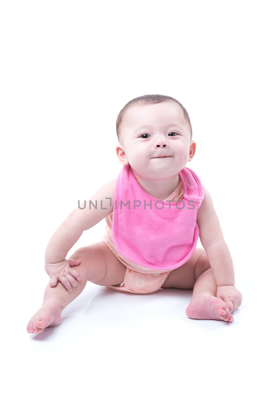 A cute 1 year old girl wearing a pink bib sitting on white.