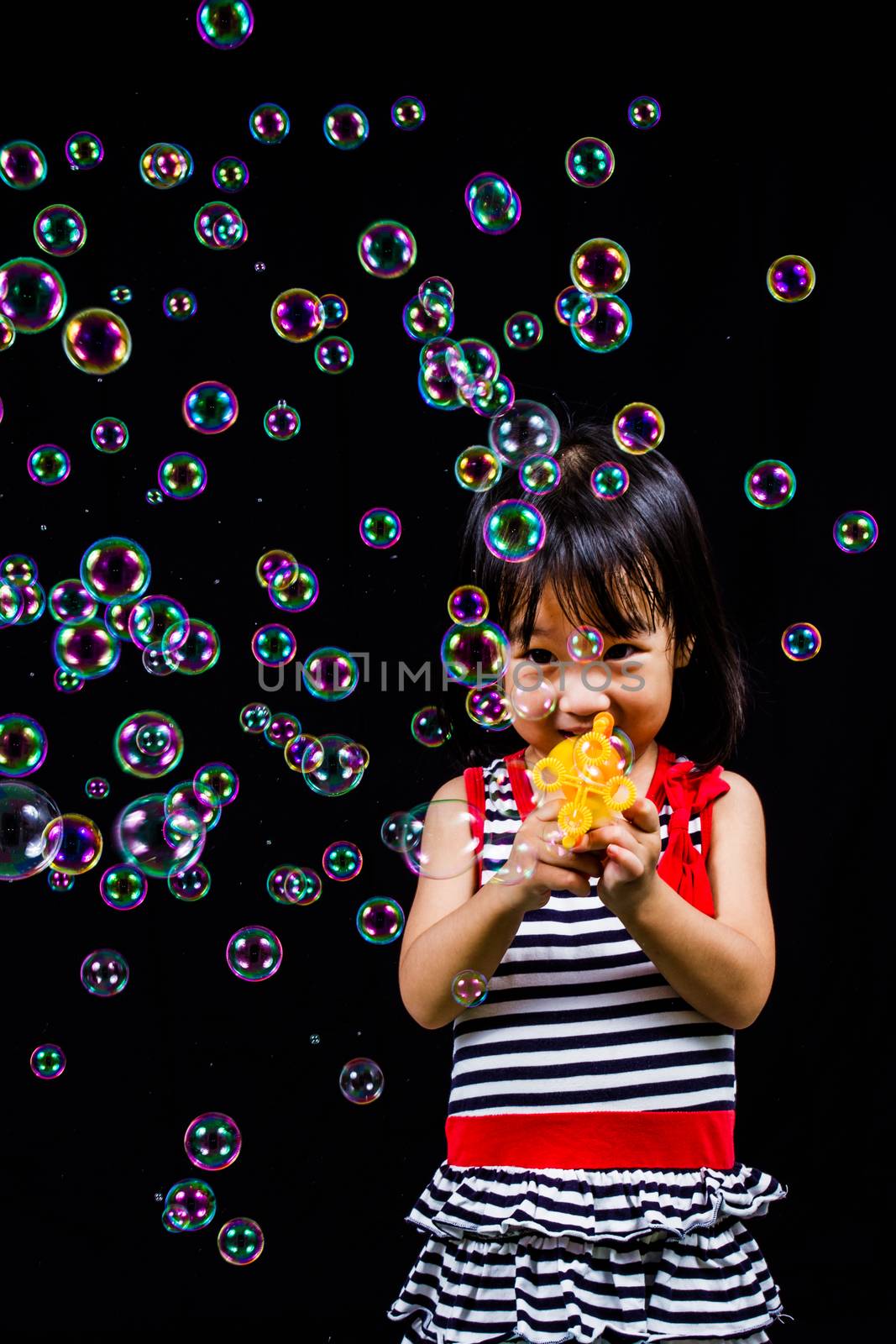 Asian Chinese children Playing Soap Bubbles in black background indoor.
