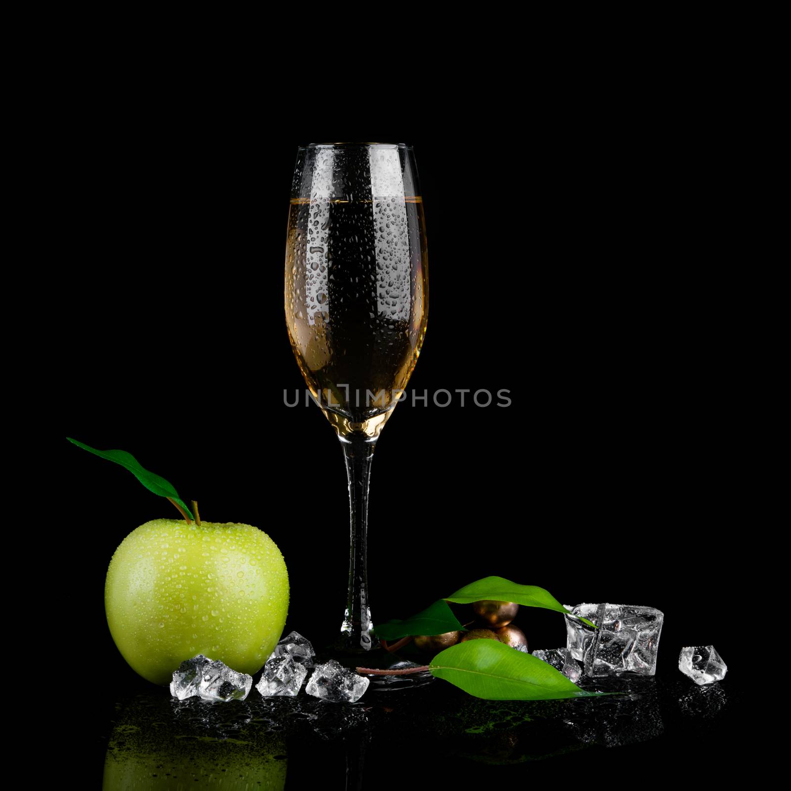 Green apple with a glass of champagne on black background
