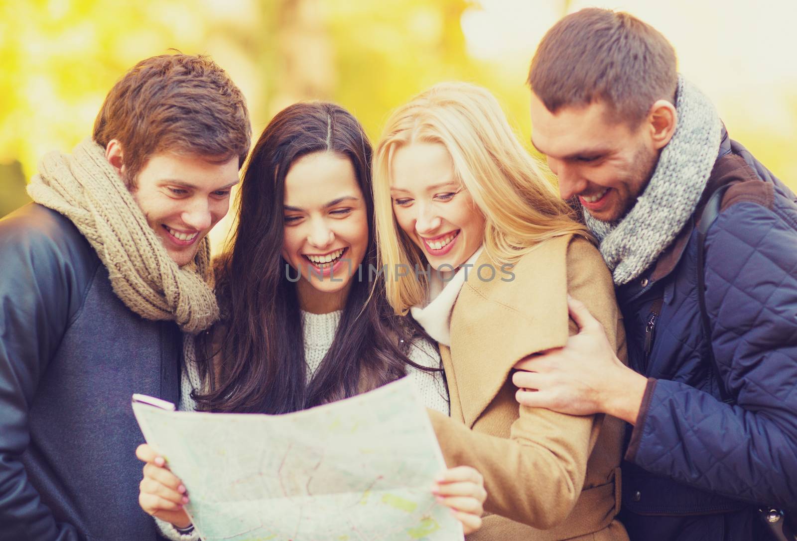 holidays and tourism concept - group of friends or couples with tourist map in autumn park