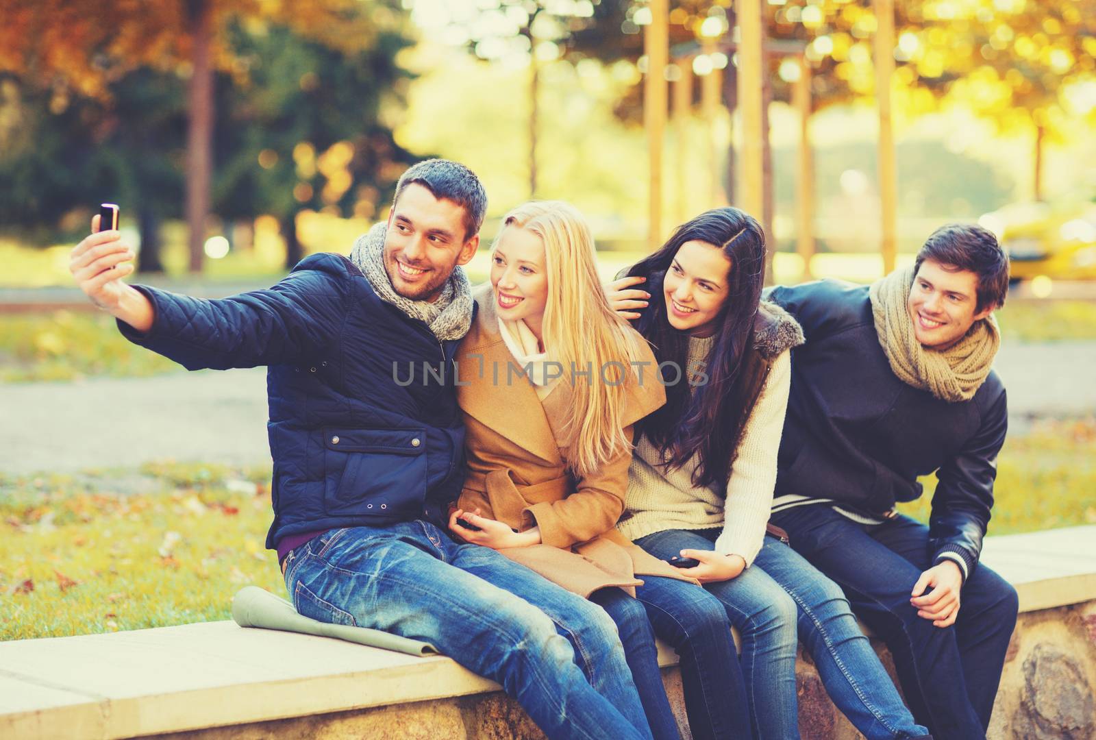 group of friends taking selfie in autumn park by dolgachov
