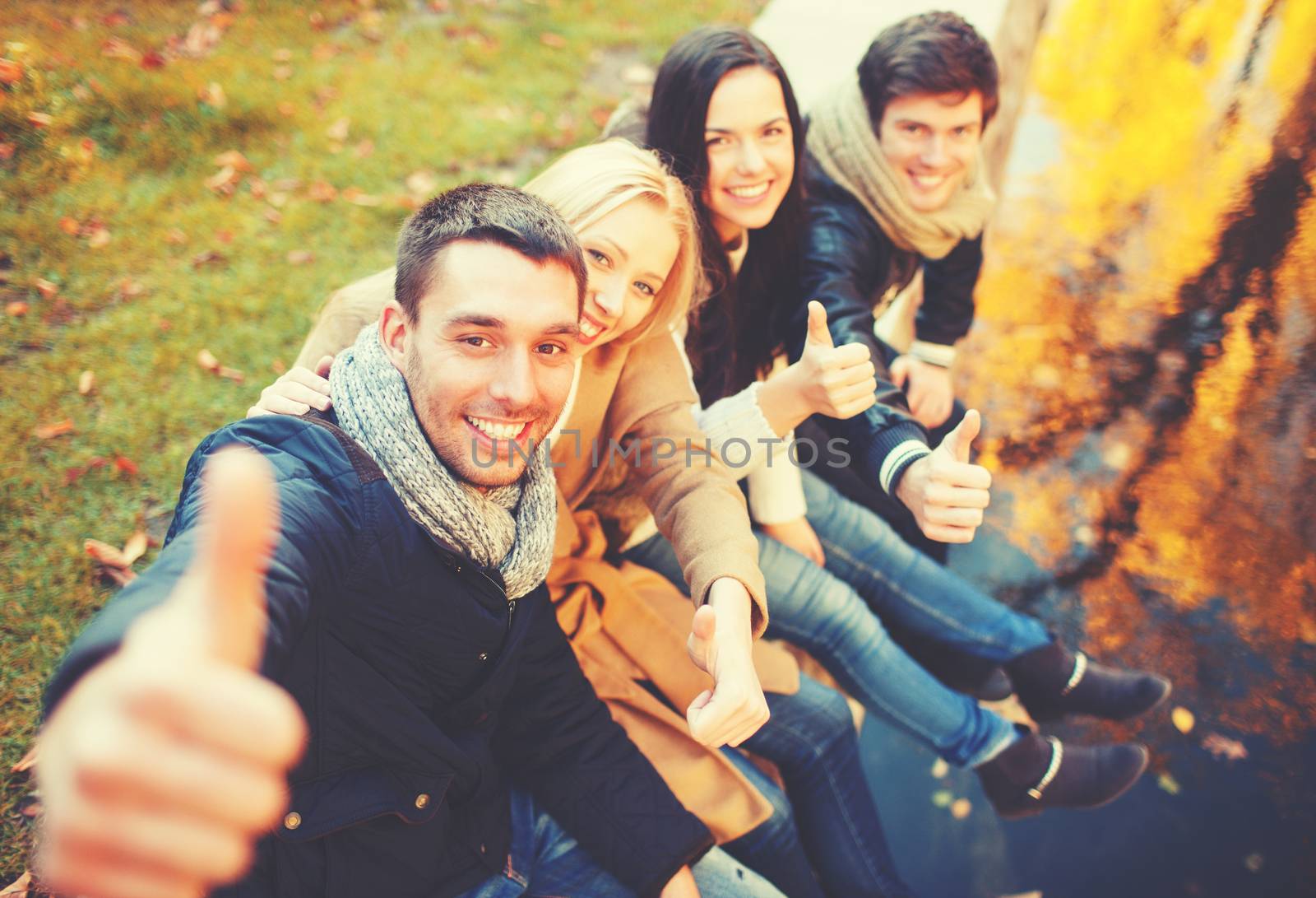 holidays, vacation, happy people concept - group of friends or couples having fun and showing thumbs up in autumn park