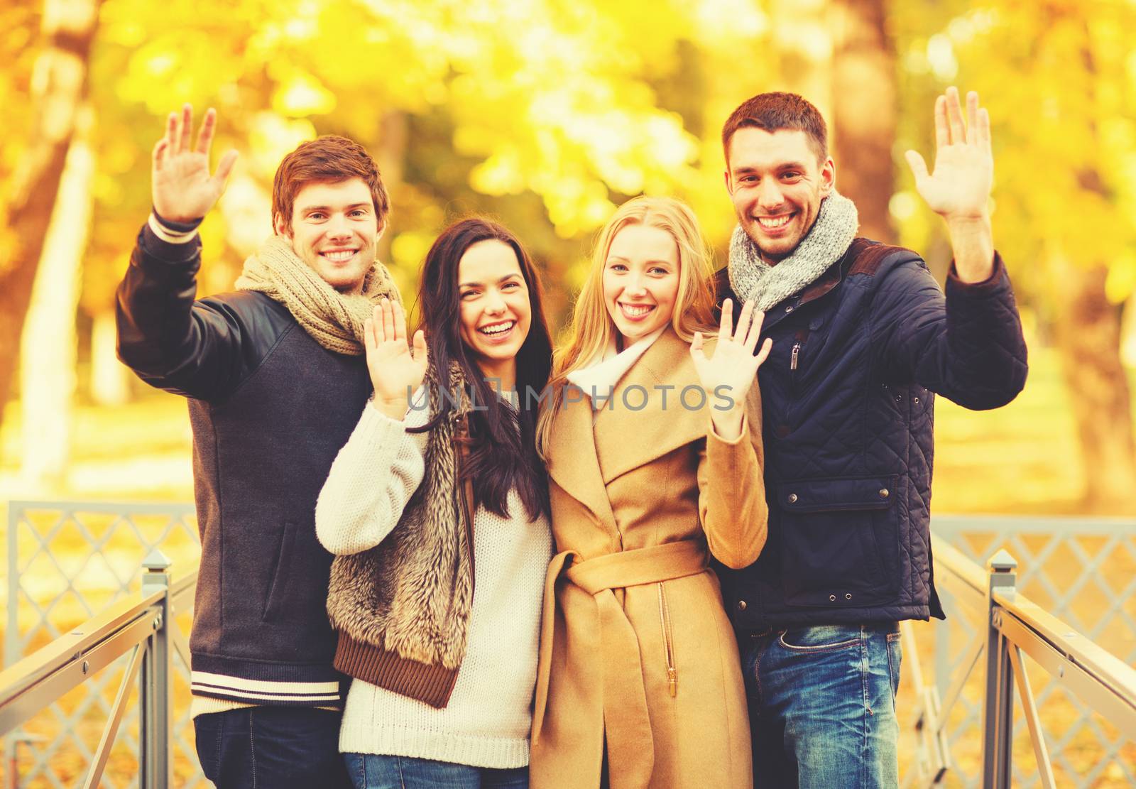 holidays, vacation, happy people concept - group of friends or couples having fun and waving hands in autumn park