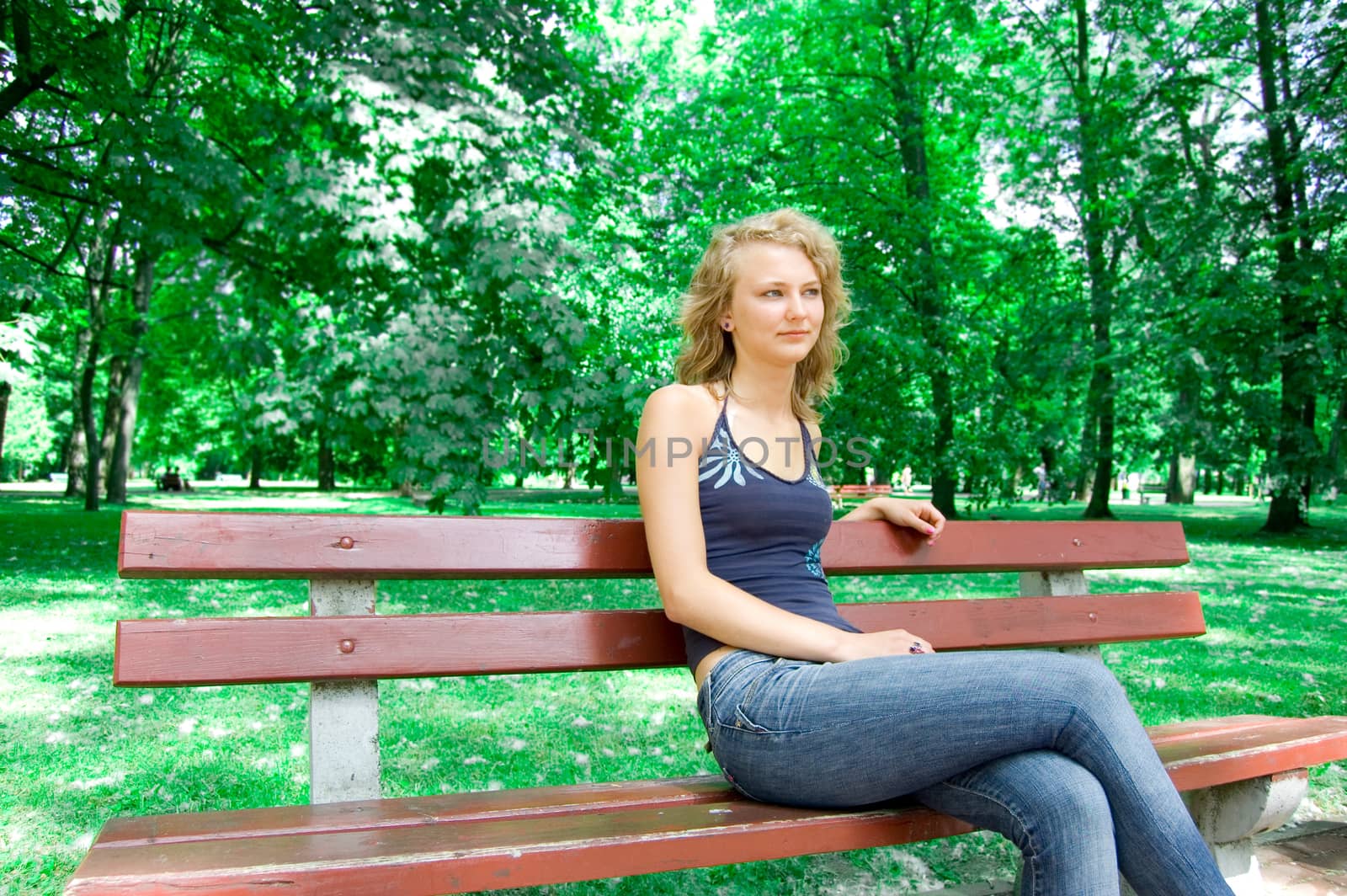Young beautiful girl sitting on a park bench.